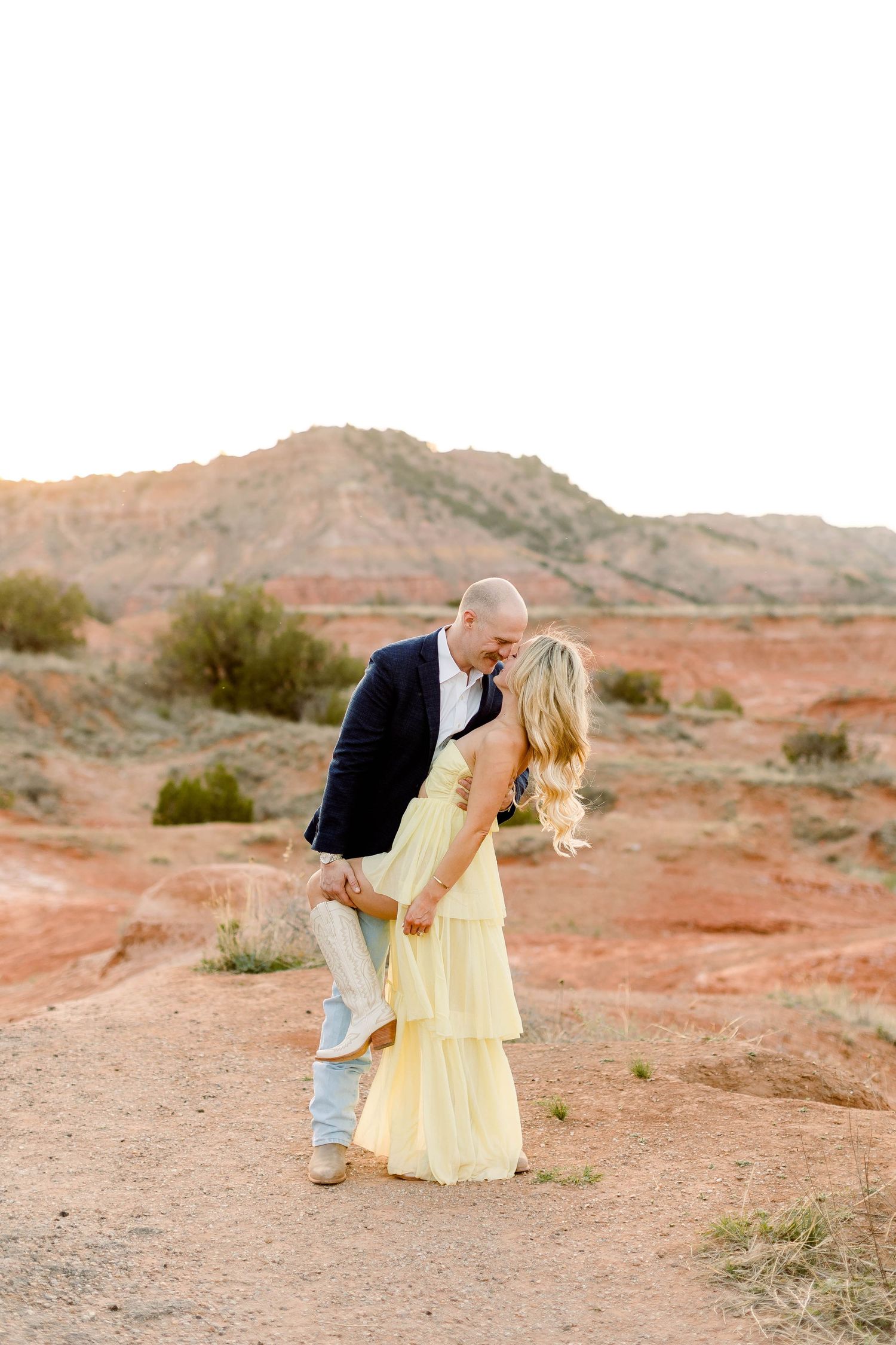 Couple sharing playful moments against dramatic desert cliffs.