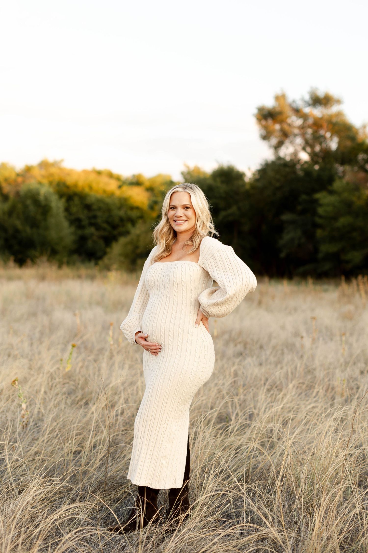 Maternity portraits in a natural setting with golden light and tall grass.