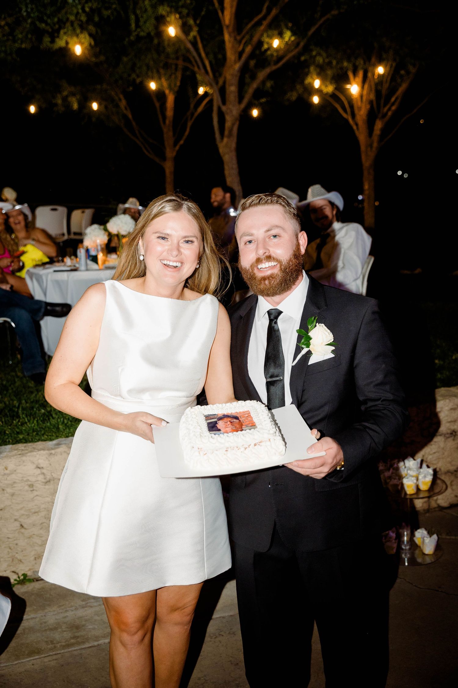 Wedding couple sharing cake and dessert at their reception under twinkling lights.