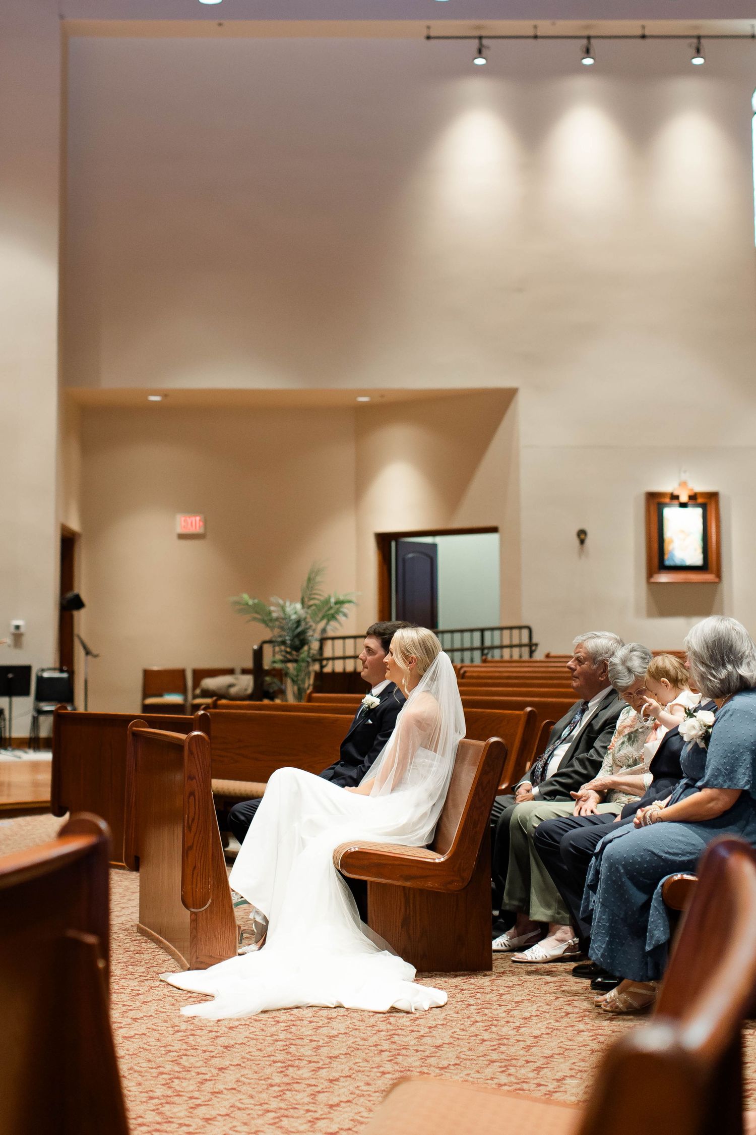 Wedding ceremony in progress inside church sanctuary with wooden pews.