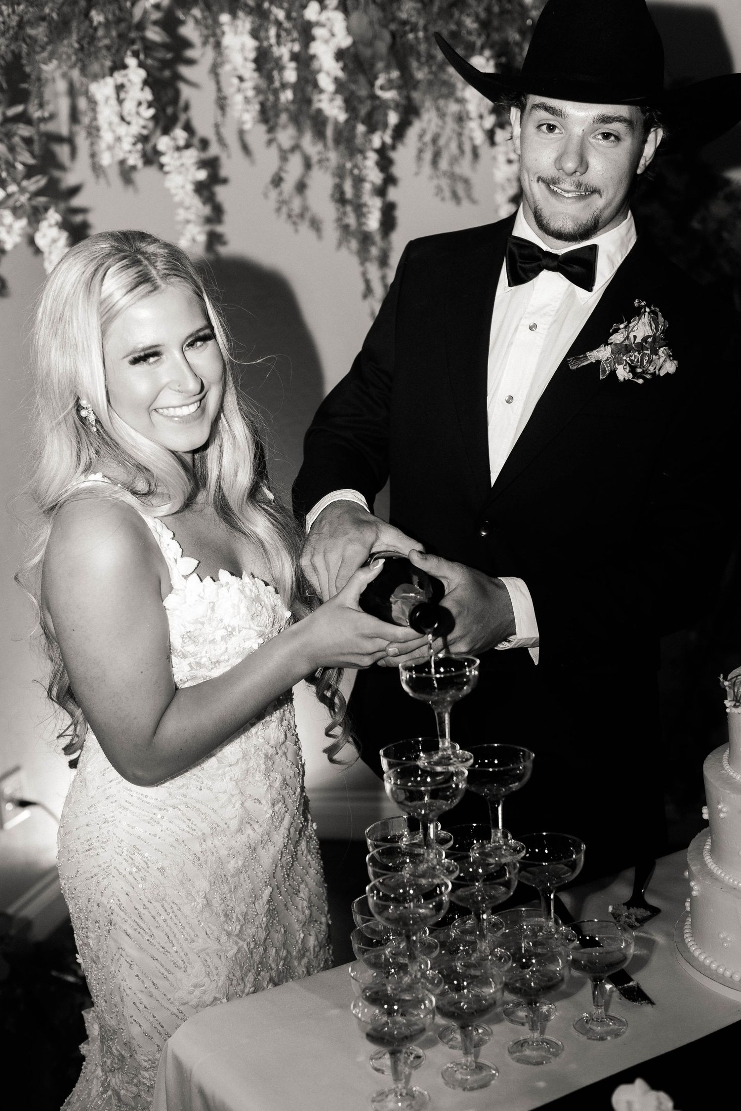 Wedding couple pouring champagne into a tower of glasses during their celebration.