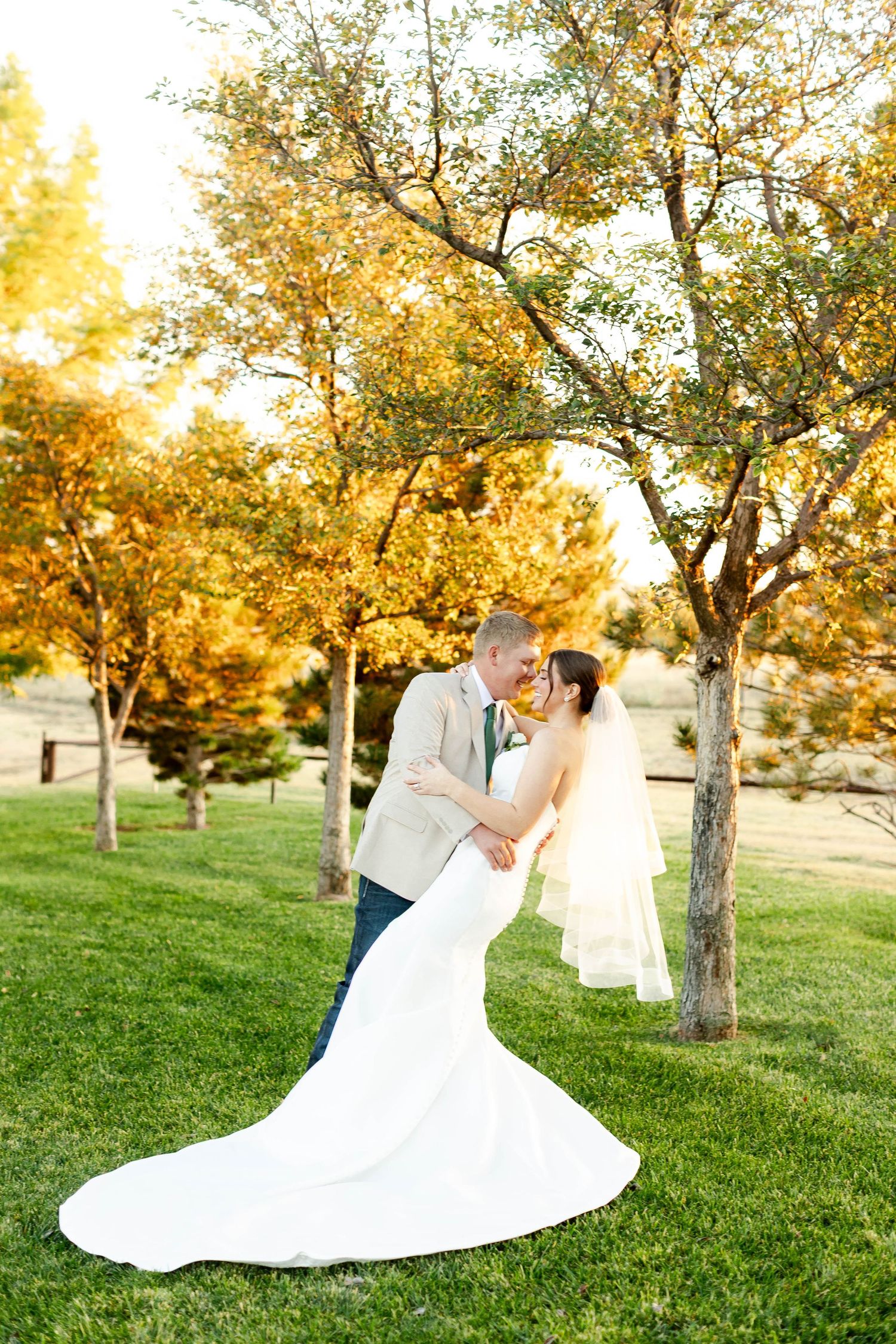 Romantic wedding photos in autumn setting with flowing white dress against golden trees.