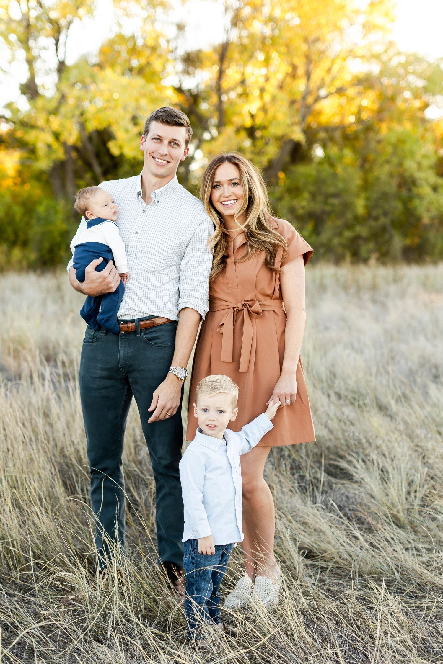 Family portrait session in golden field with tall grass at sunset.