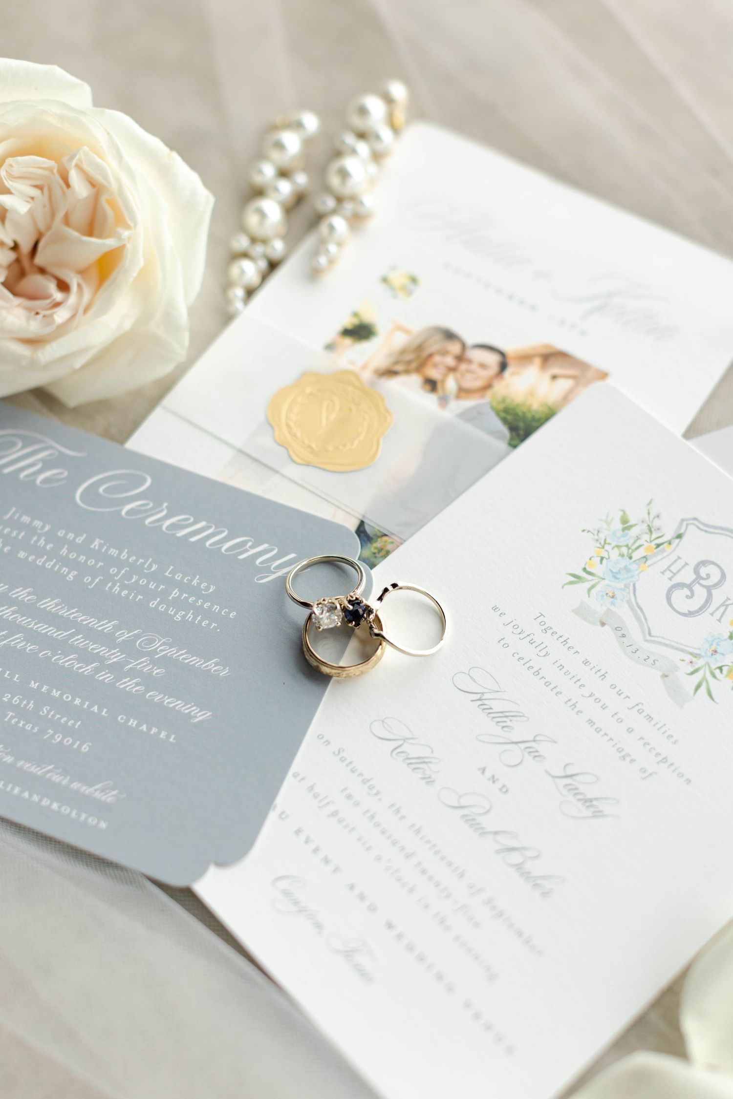 Wedding invitation suite in grey and white with rings, pearls and cream rose detail.