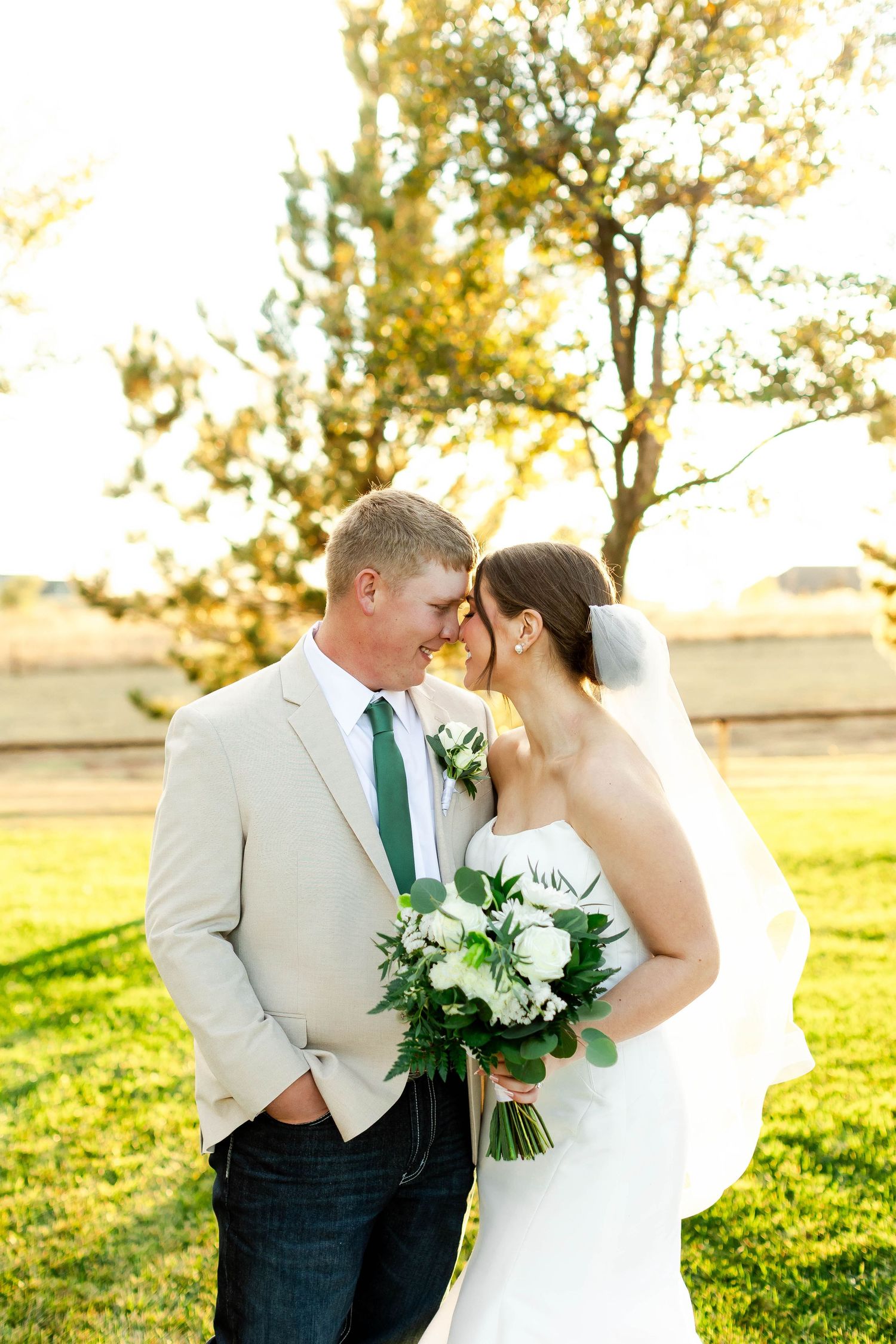 Romantic wedding portraits in golden sunlight with white floral bouquet.