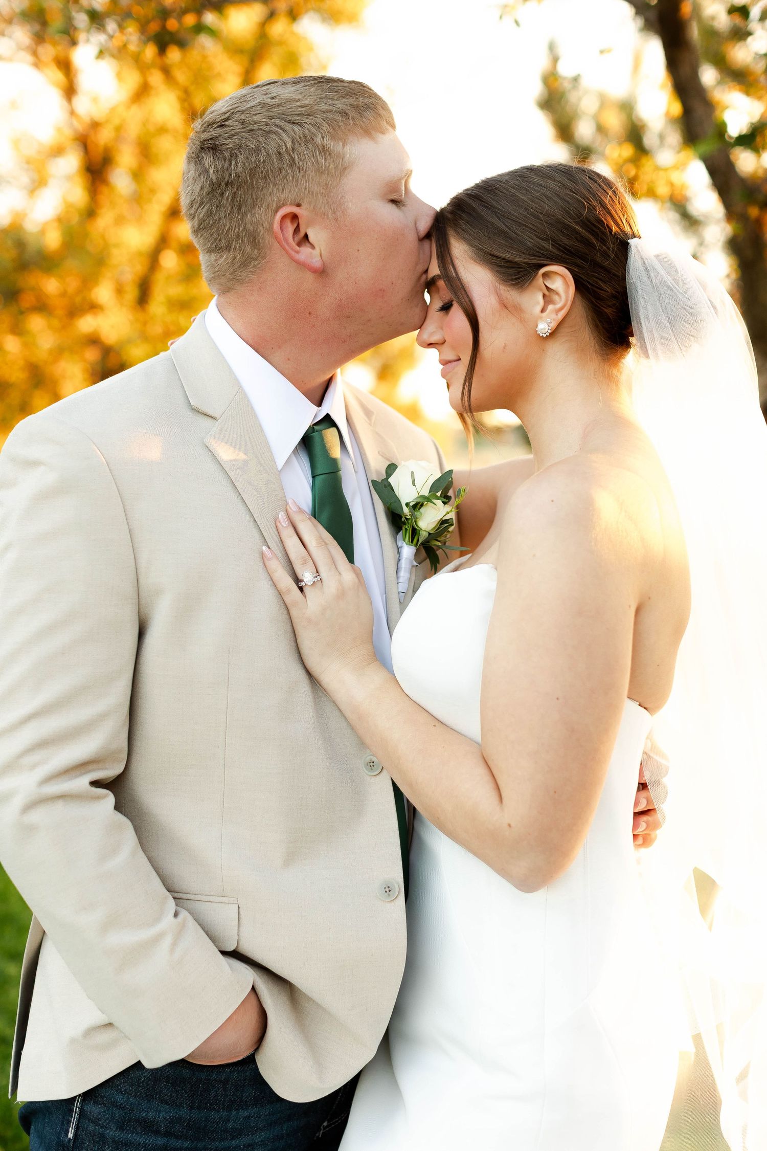 A romantic wedding couple embraces during sunset photos in formal attire.