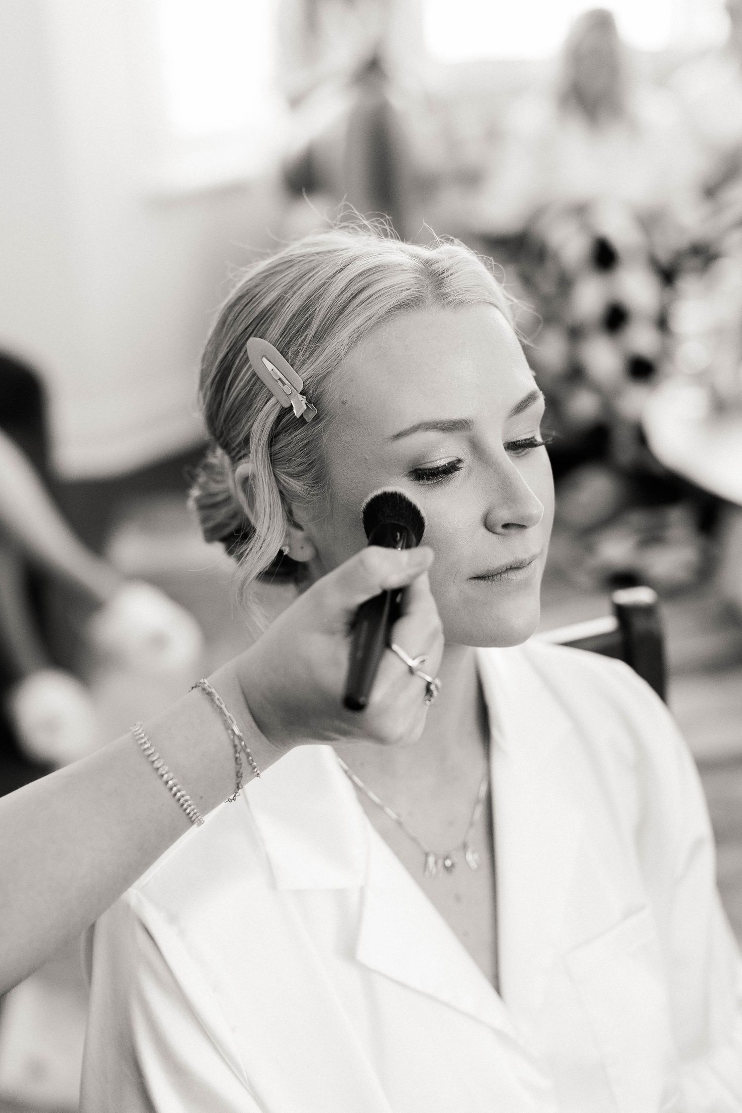 Close-up shots of bridal makeup application and hair styling preparations in black and white.