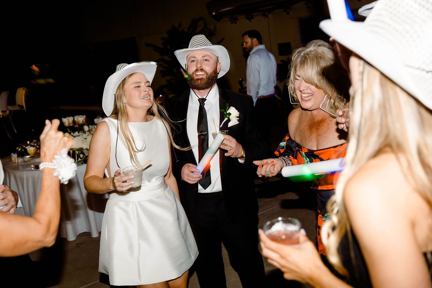Party guests dancing and celebrating at a nighttime wedding reception.