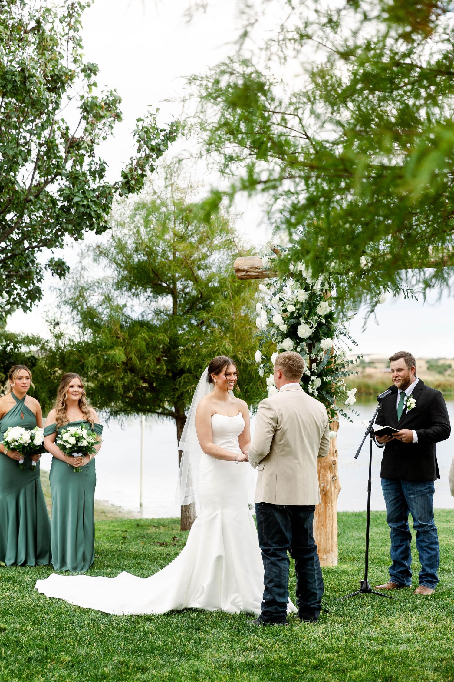 Wedding party poses for photos on a grassy hillside during an outdoor celebration.