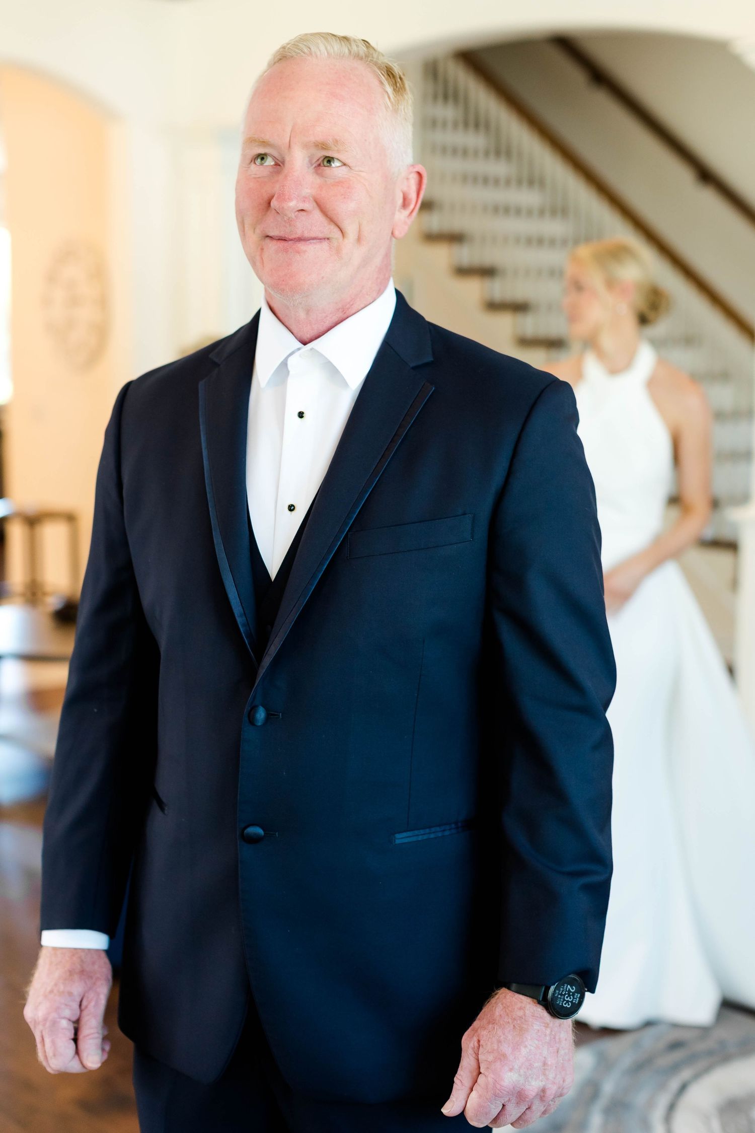 Person wearing a classic black tuxedo and bow tie stands in a formal setting.