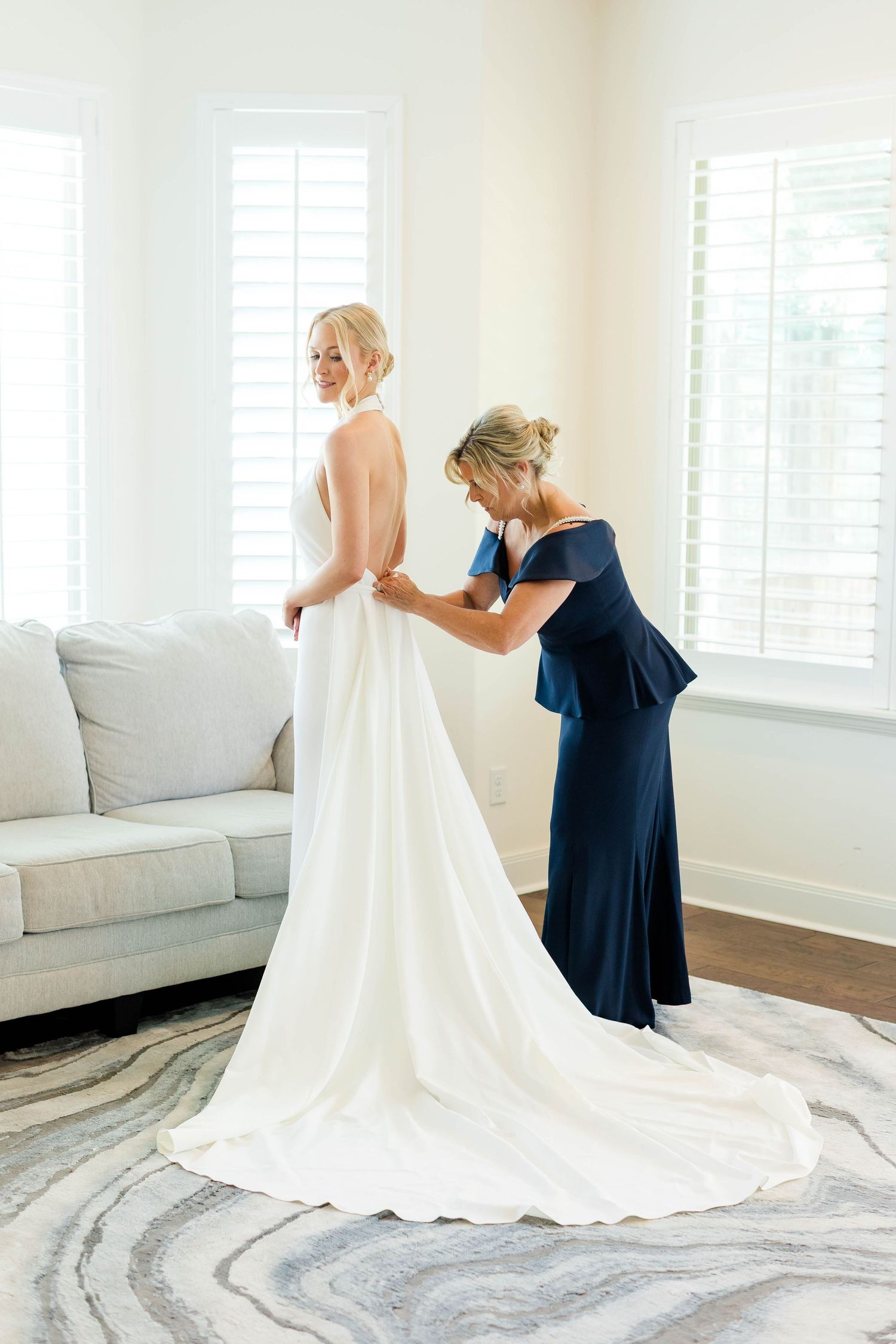 Wedding dress train being arranged on grey marble patterned floor.