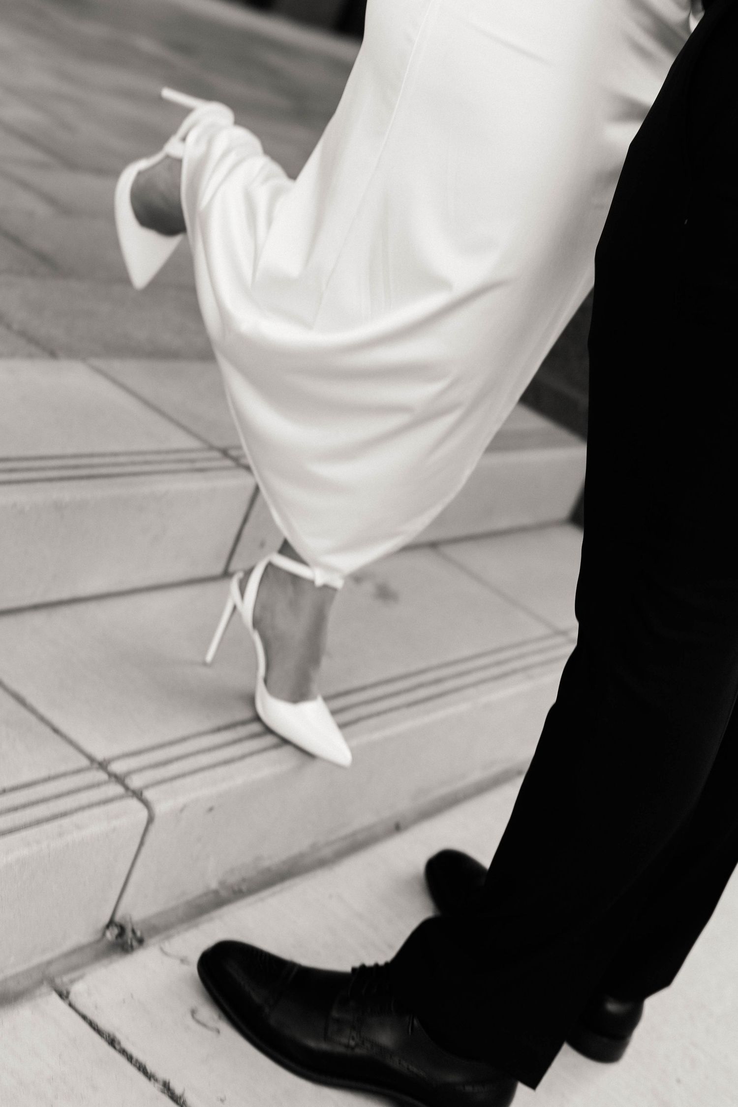 Close-up of formal shoes and dress hem during romantic moment.