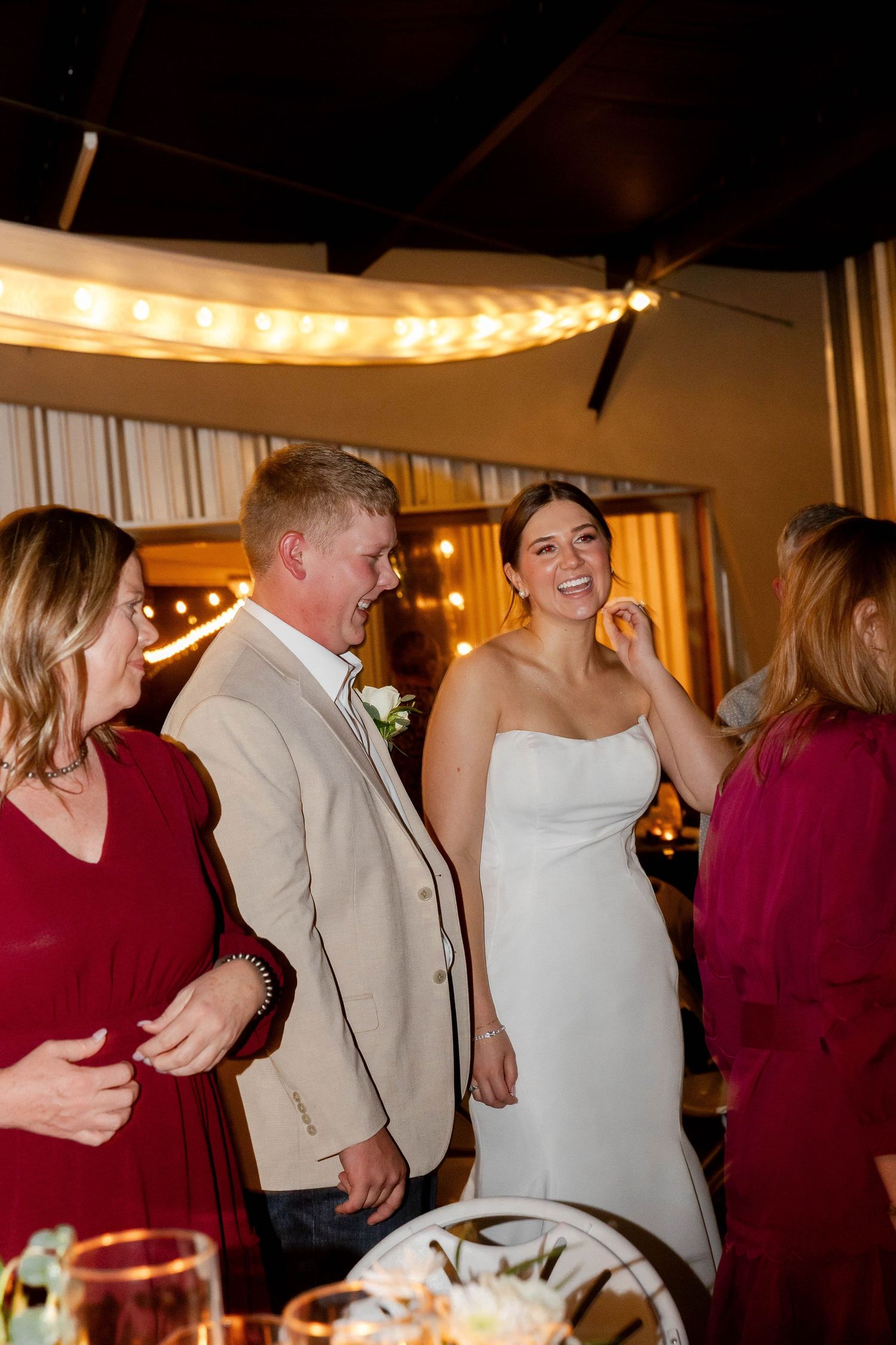 Wedding guests in burgundy and beige attire dance and celebrate at an evening reception.