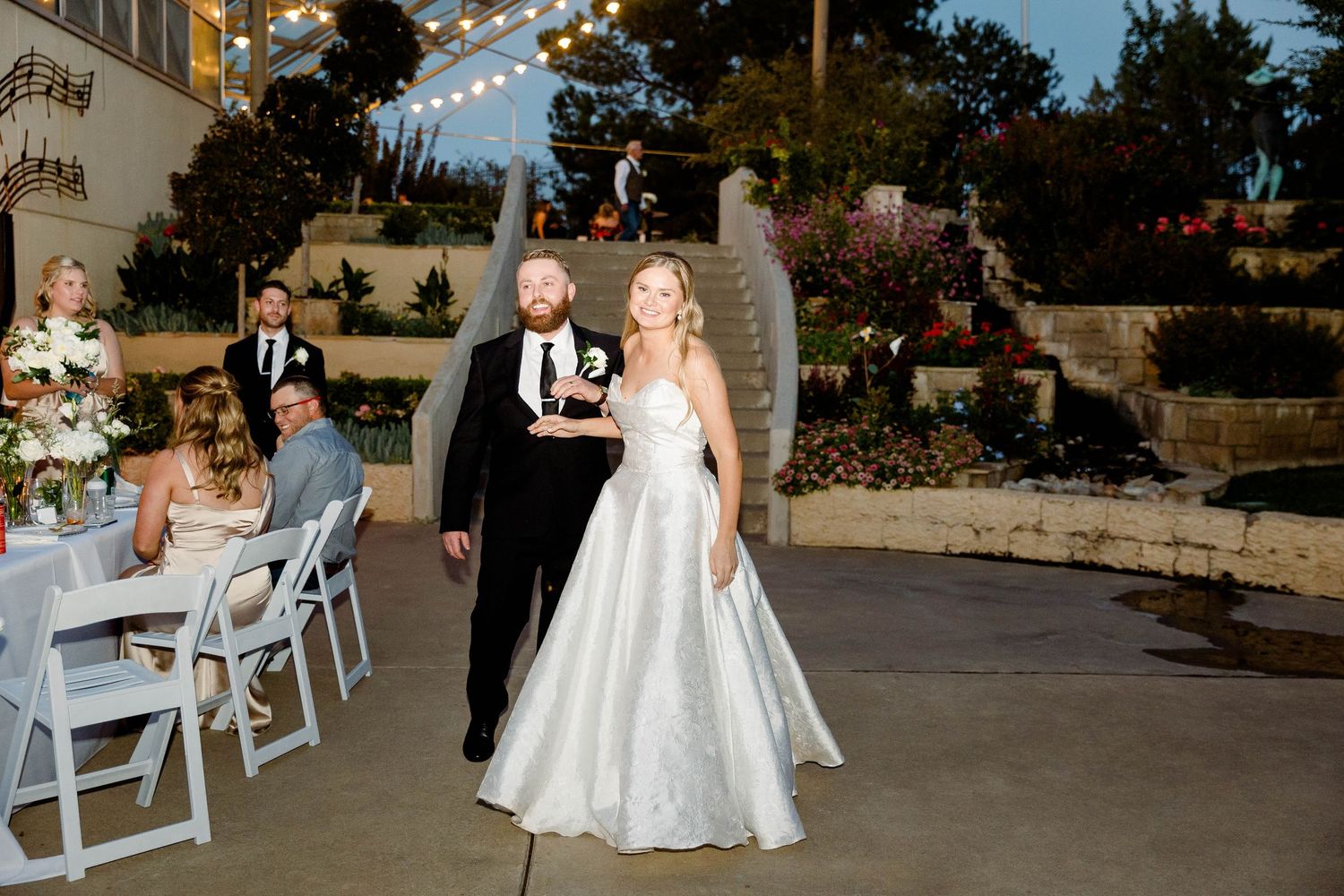 Wedding reception dance floor scene with white chairs and string lights at twilight.