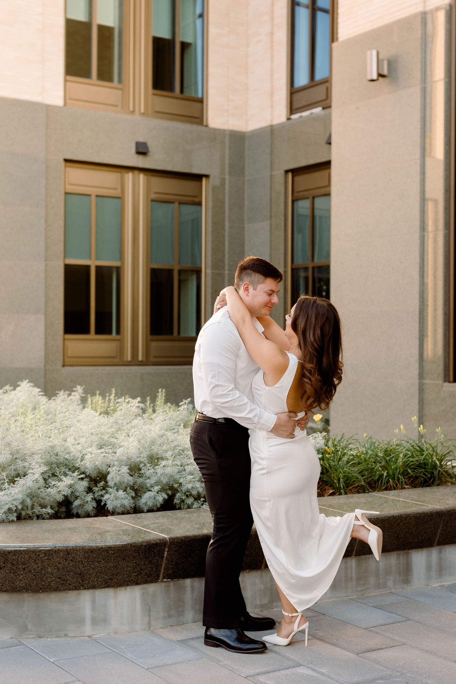 Couple in white clothing shares dynamic poses during architectural photoshoot.
