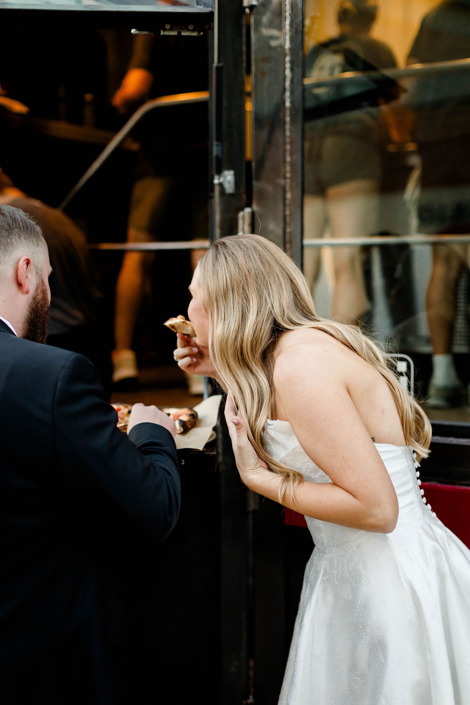 Wedding couple shares playful moments by dark industrial doors.