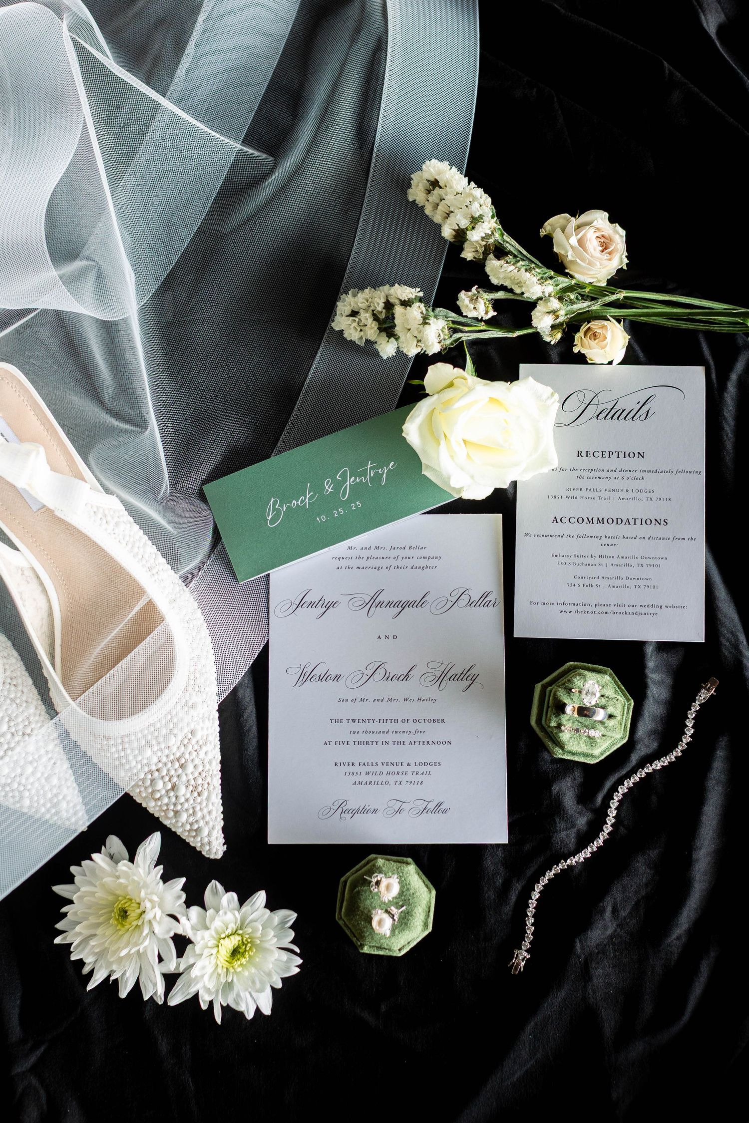 Wedding invitation suite with white flowers, sparkly bridal shoes, and green accents on black velvet background.