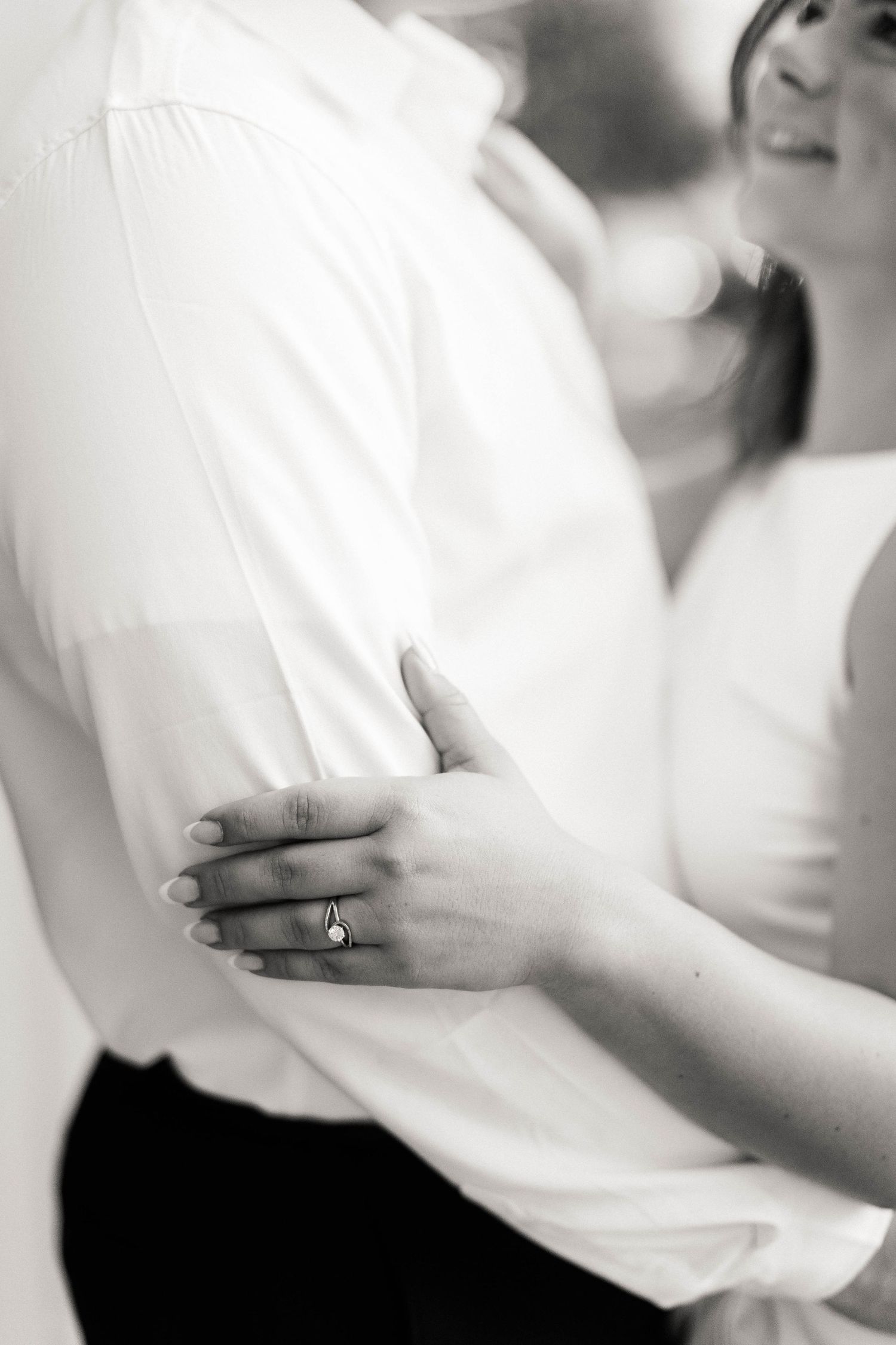 A black and white close-up series showing details of an engagement ring and embracing couple.