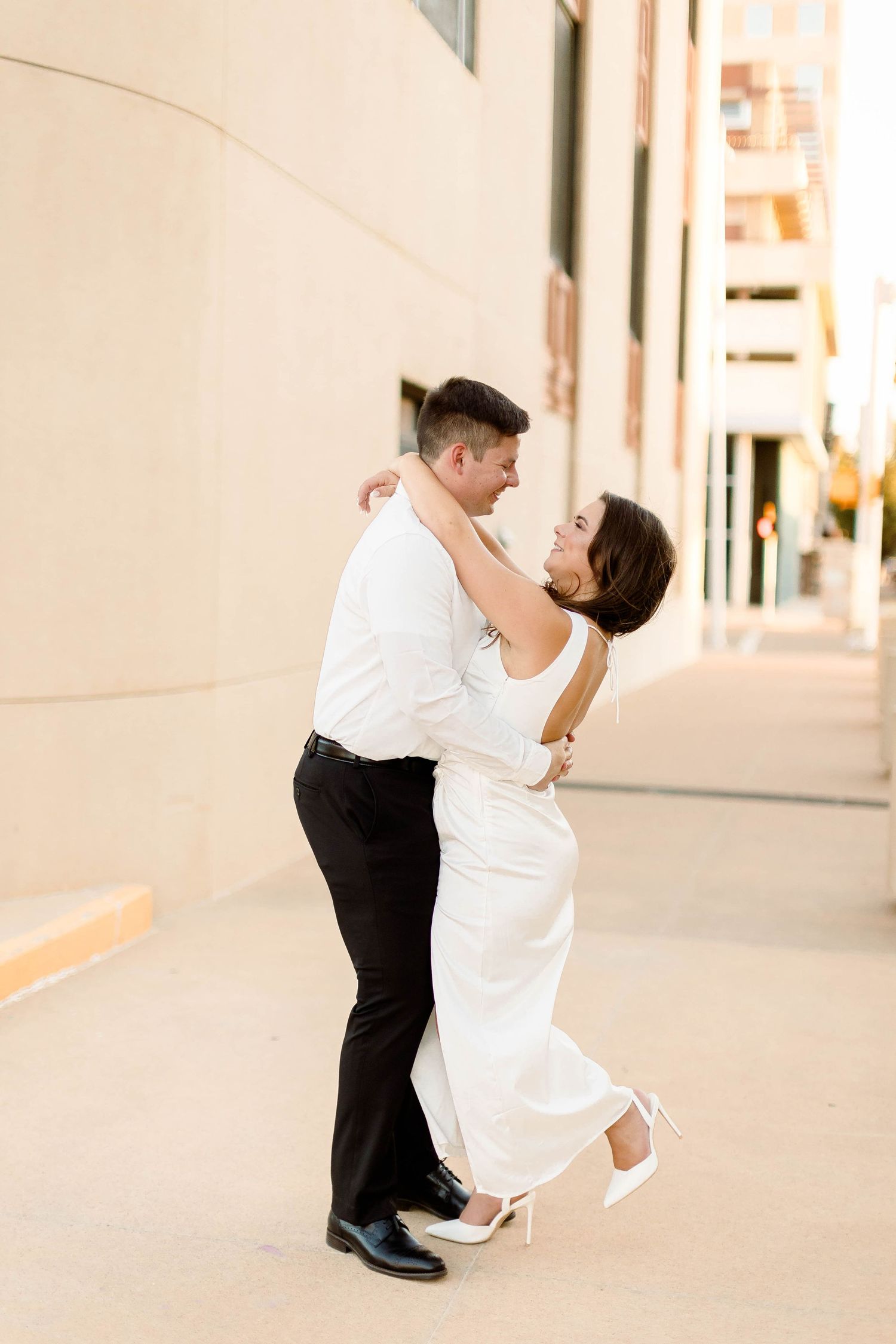 A couple shares a romantic dance moment in an outdoor urban setting.