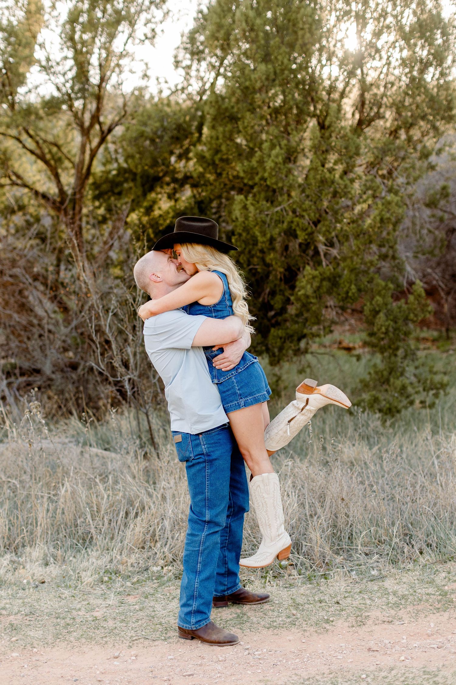 Playful couple in denim share intimate moments on a rustic outdoor trail.