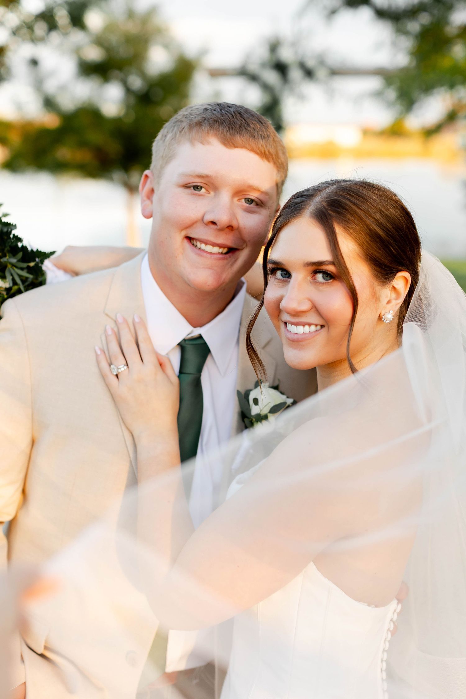 Intimate wedding portrait under flowing white veil during sunset.