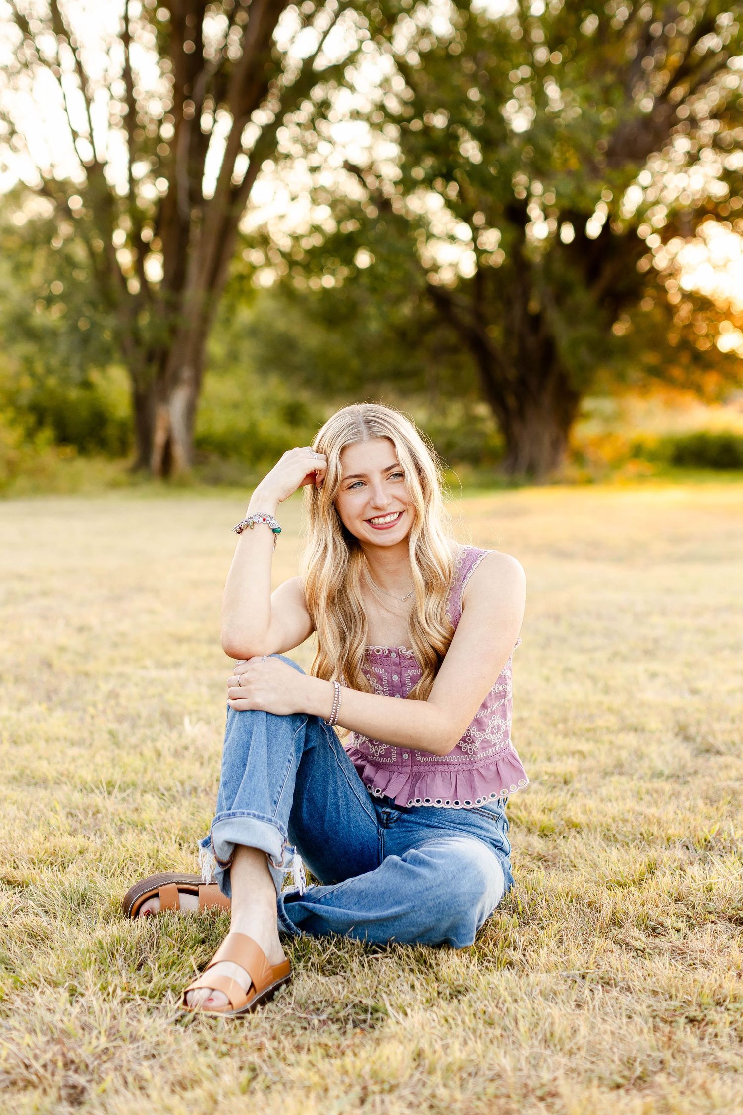 Person relaxing on grassy field during golden hour sunset. senior session