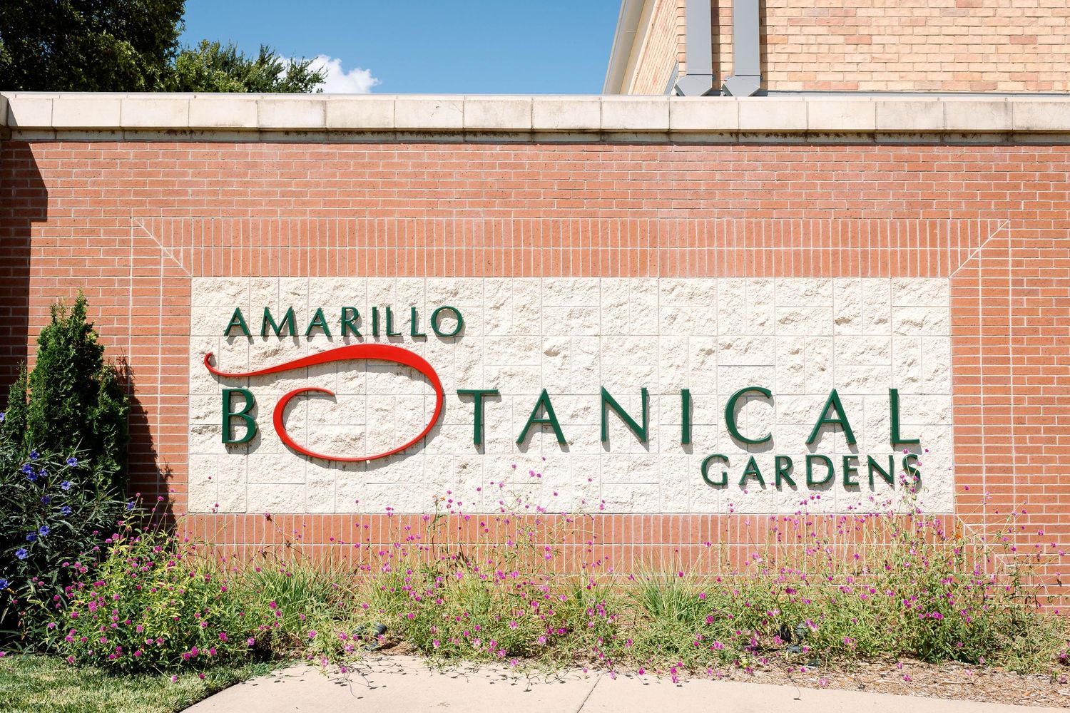 Sign for the Amarillo Botanical Gardens displayed on a brick wall.