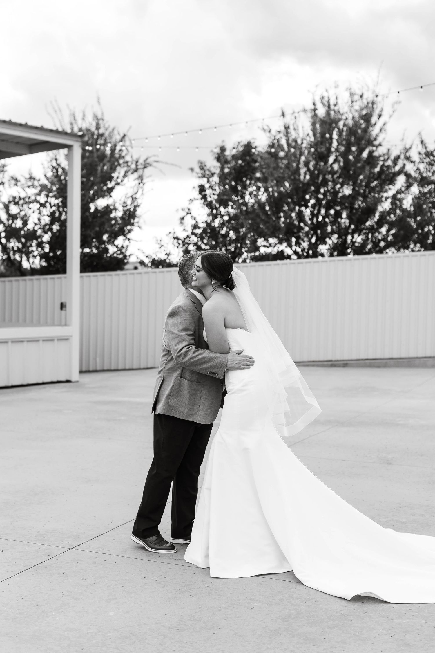 A romantic black and white wedding photo of a couple embracing on an outdoor patio.