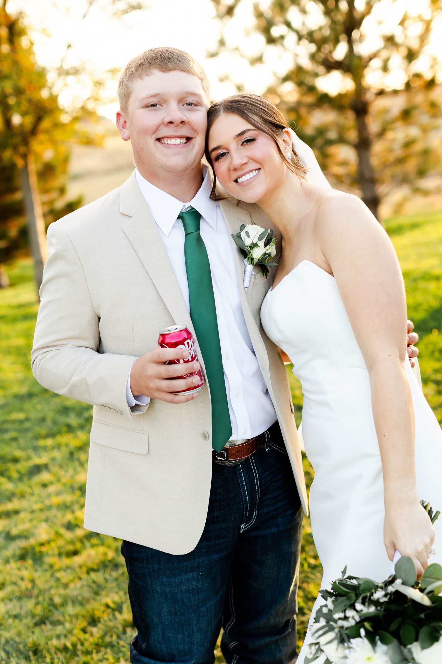 A couple in wedding attire shares a joyful moment together during golden hour.