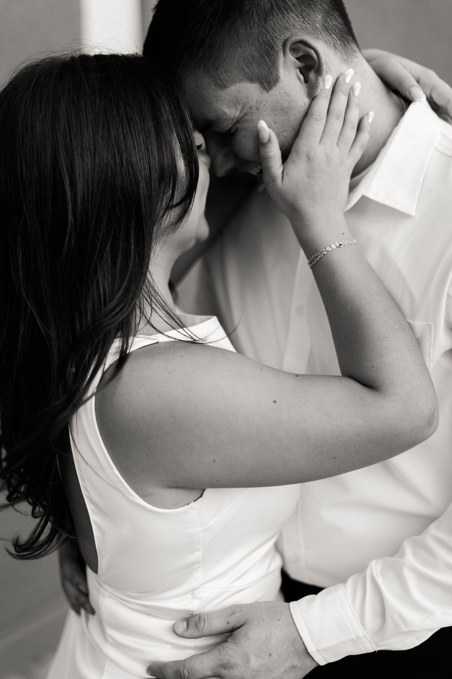 A black and white portrait of a couple sharing an intimate embrace.