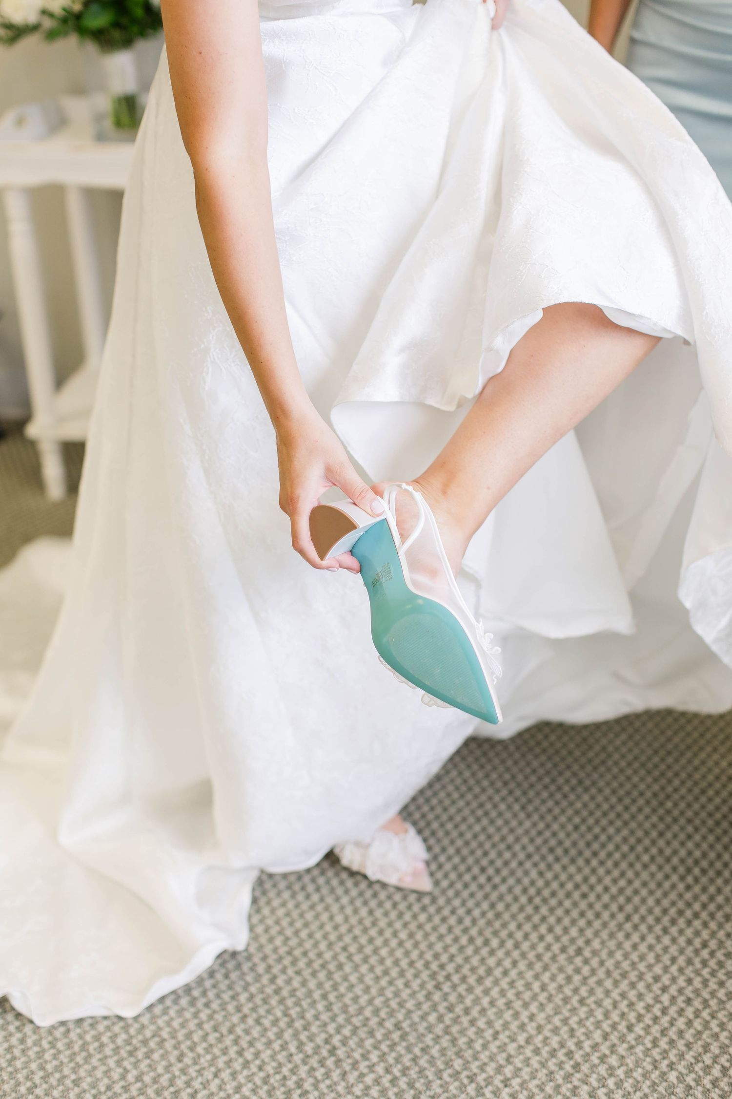 Close-up of mint green bridal shoes peeking under white wedding dress.