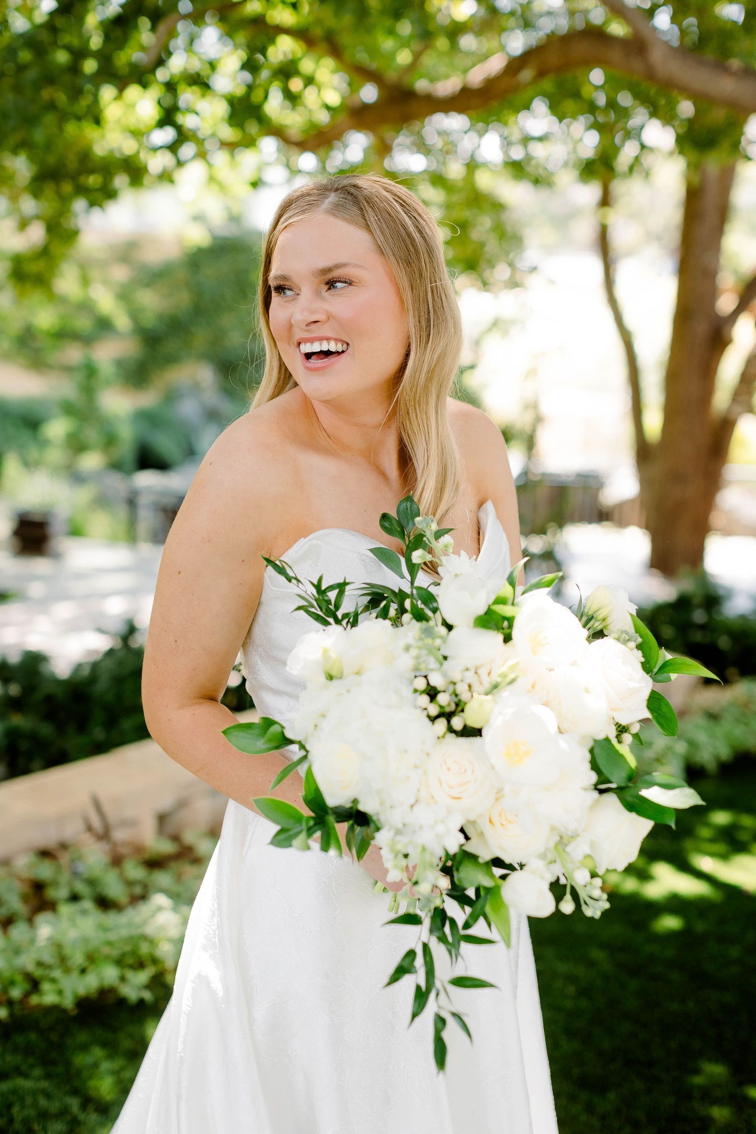 Elegant bridal portrait with white floral bouquet in an outdoor garden setting.