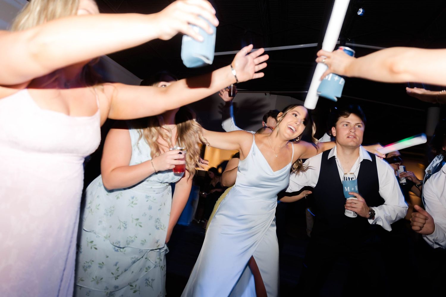 Wedding party members dancing in a line at the reception celebration.