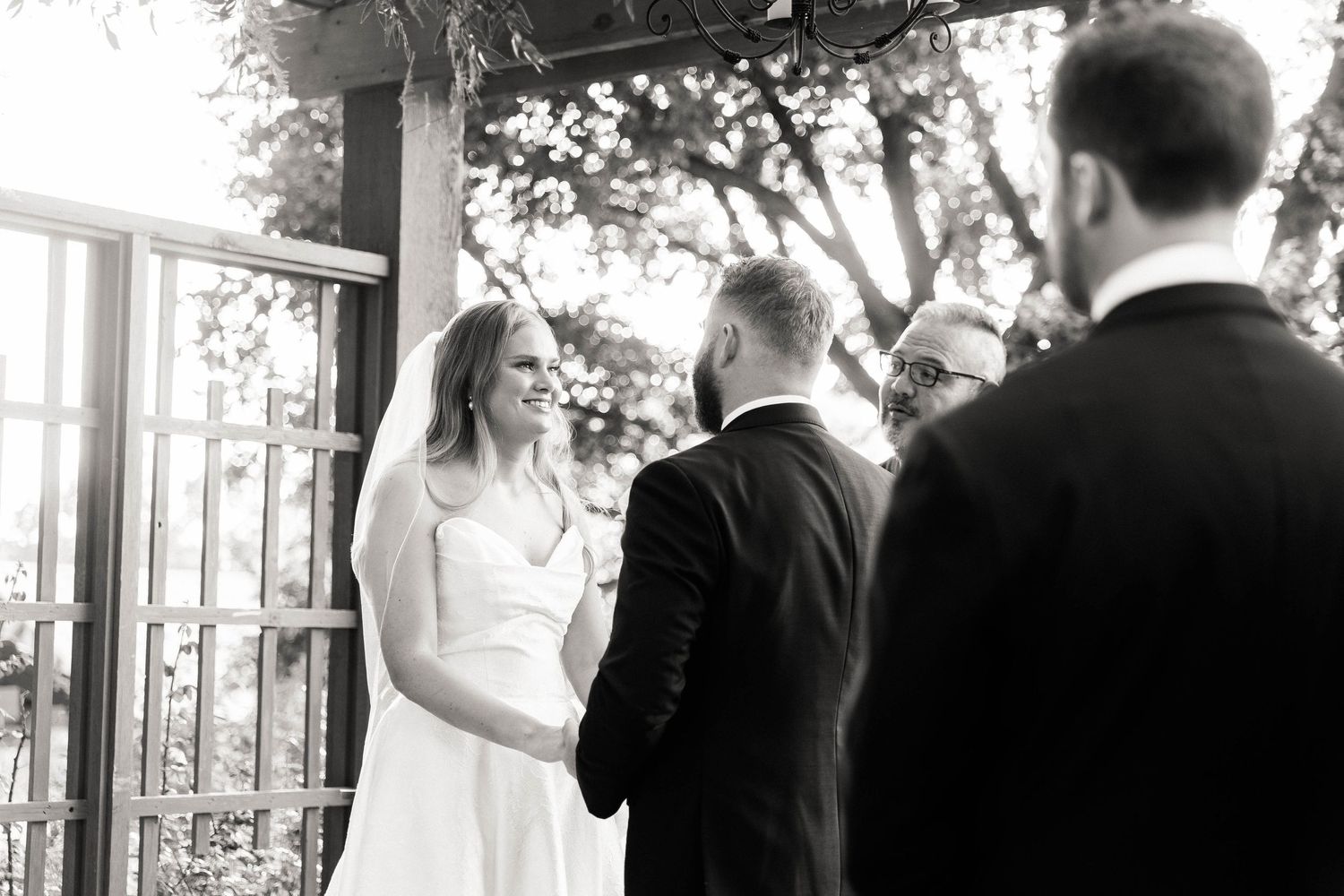 Black and white photograph of a wedding ceremony moment under an outdoor pavilion.