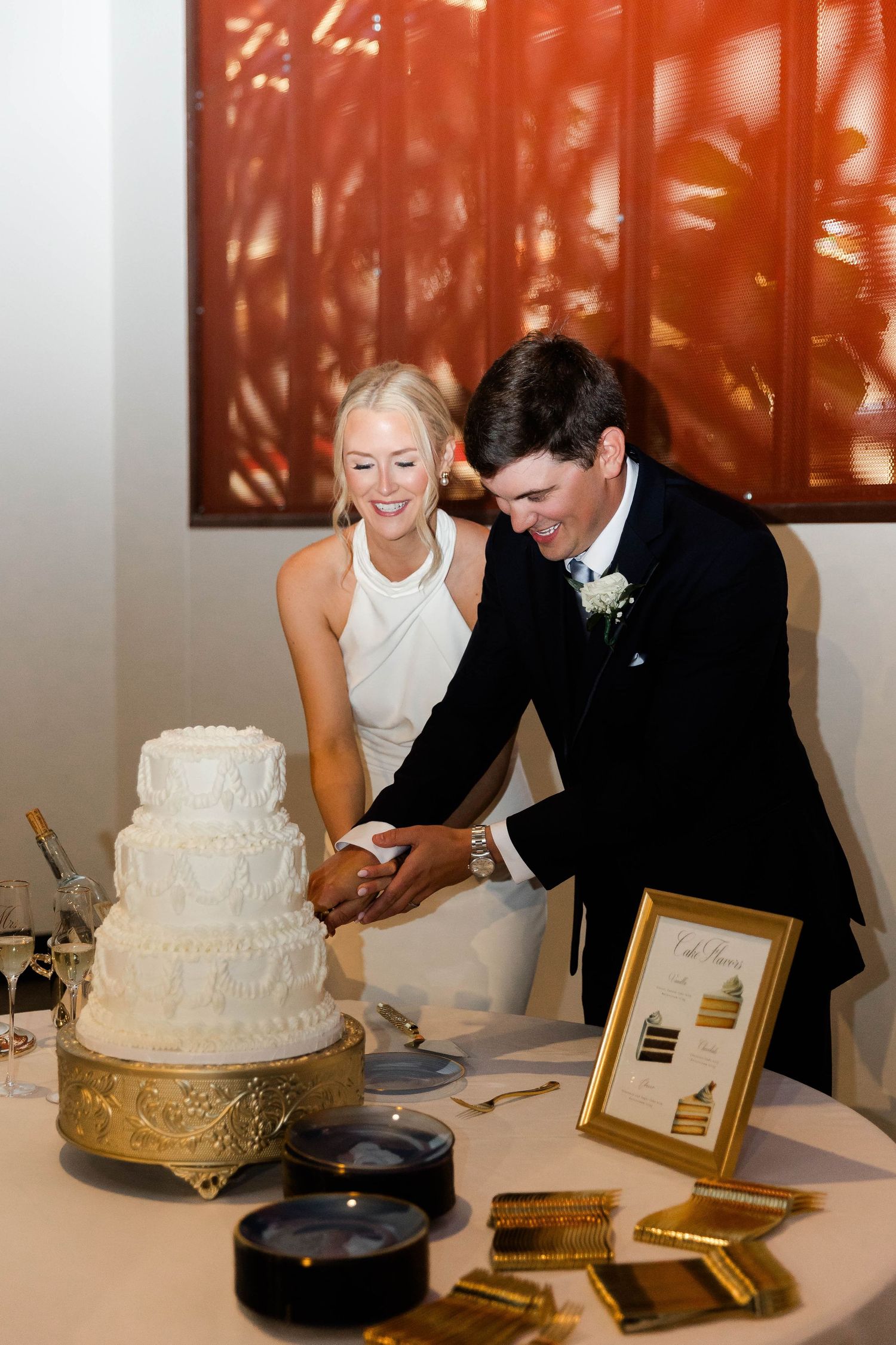 Couple cutting their white tiered wedding cake at a reception.