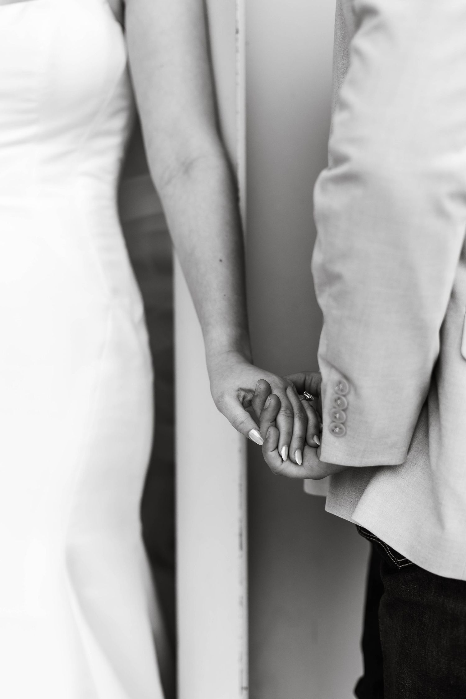 A close-up view of hands wearing formal attire in a wedding party lineup.