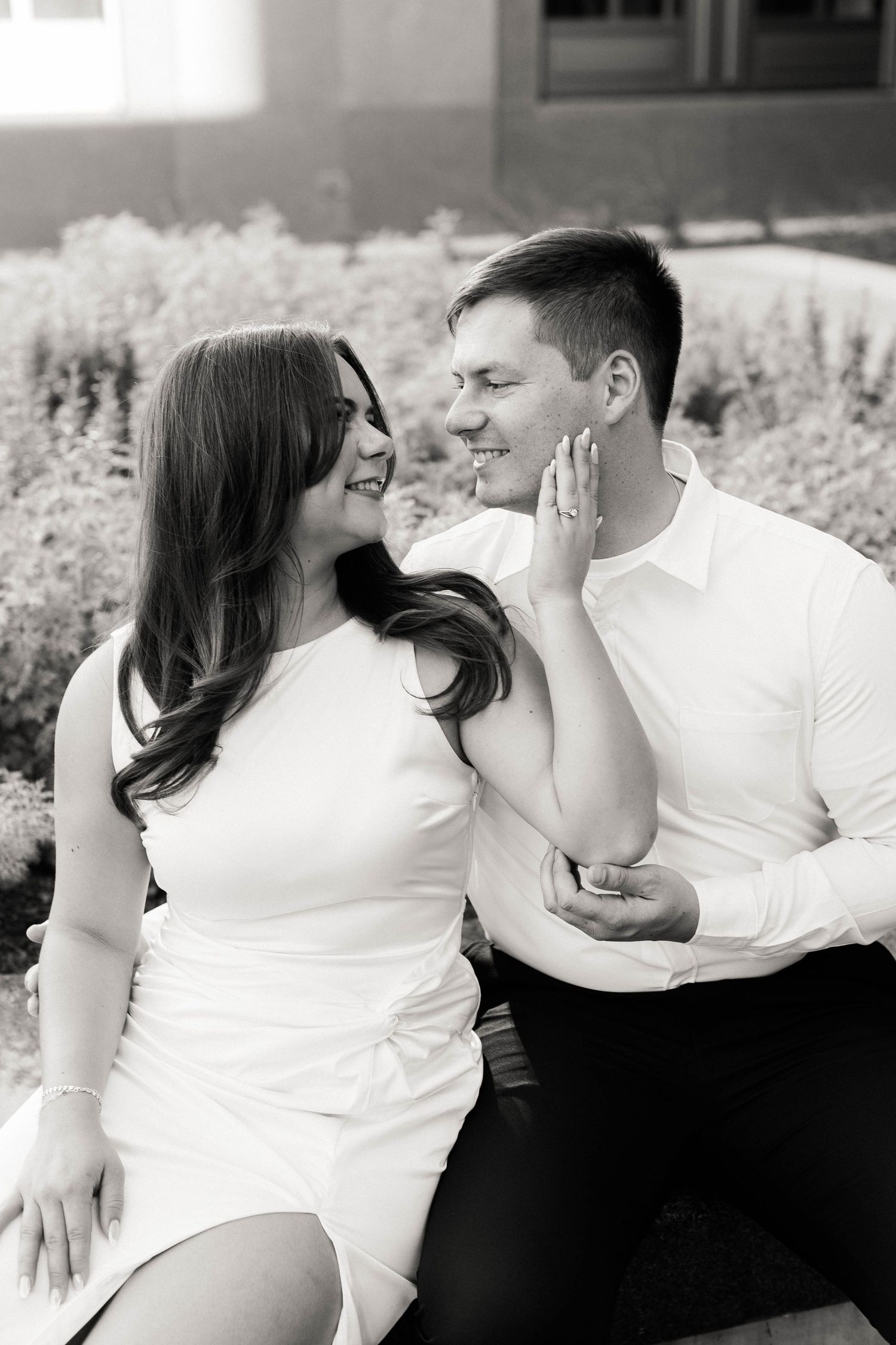 Black and white portrait of a couple sharing intimate moments on outdoor steps.
