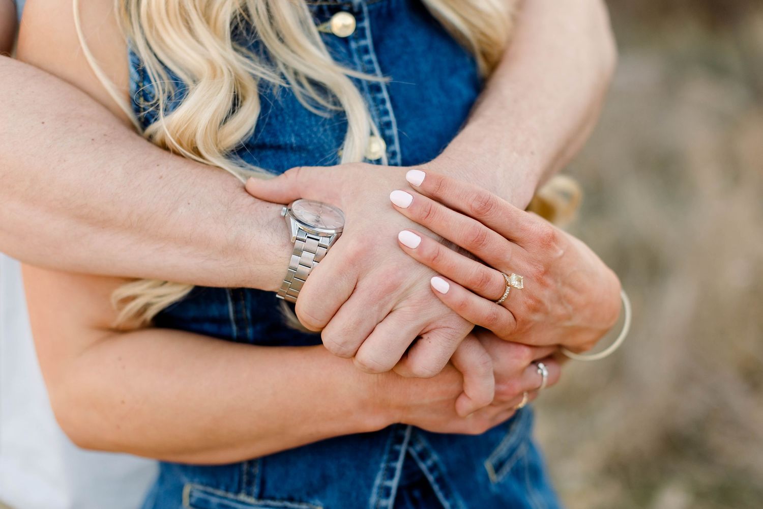 Close-up details of hands and denim clothing during an outdoor couples photoshoot.