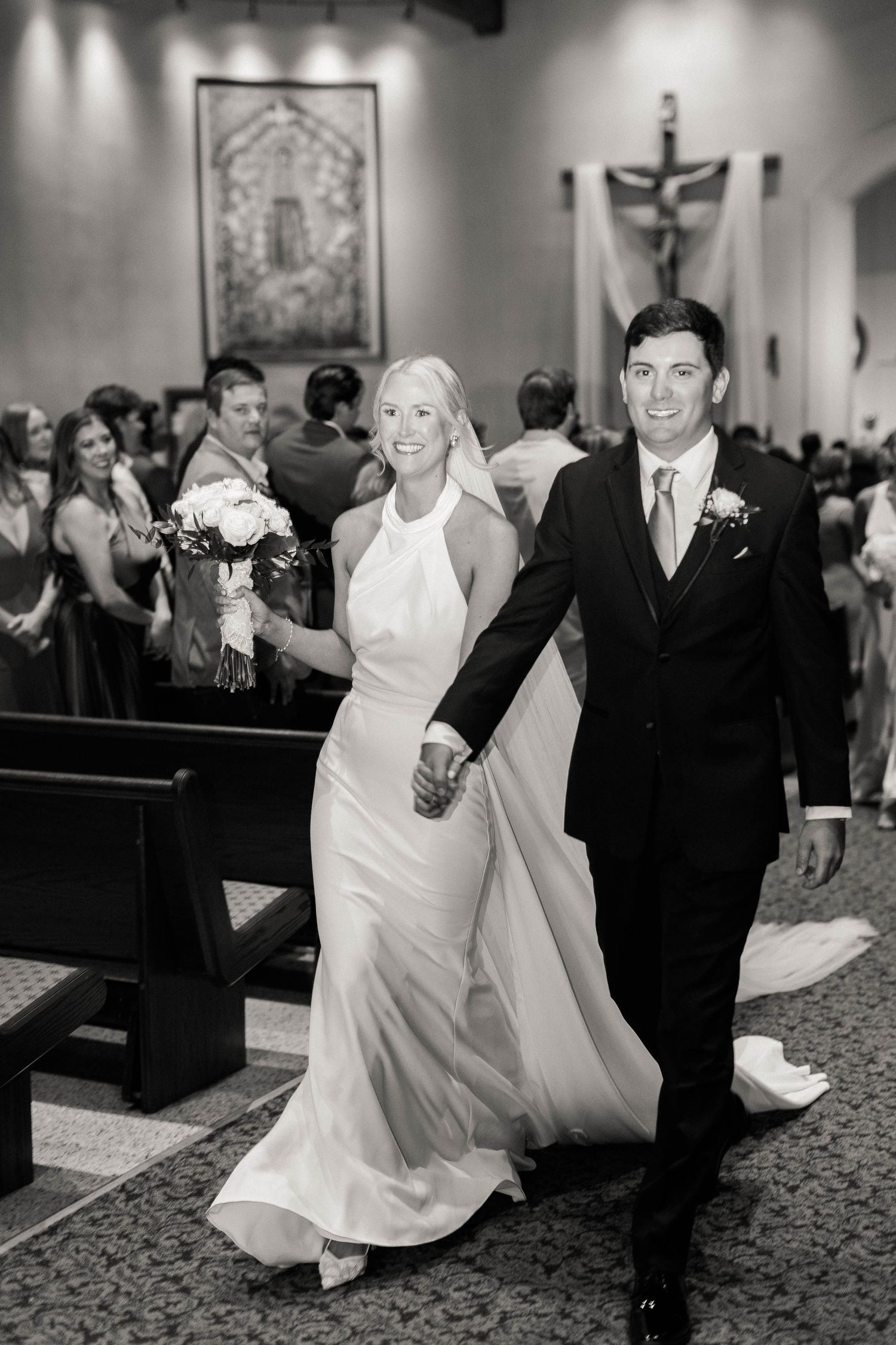 Wedding party dancing and celebrating in a church reception hall with black and white photography.