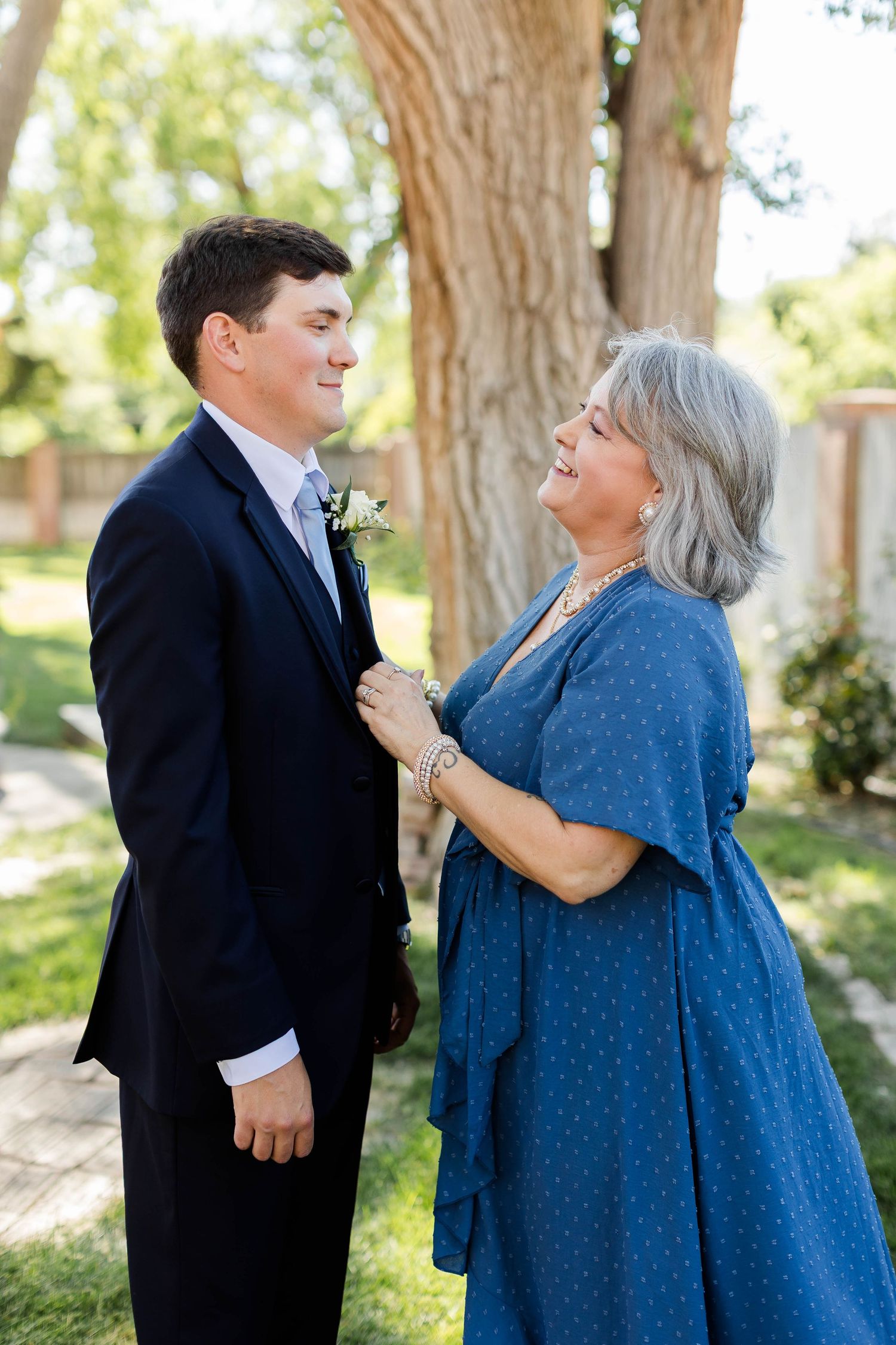Young man in suit and woman in blue dress sharing a joyful moment outdoors.