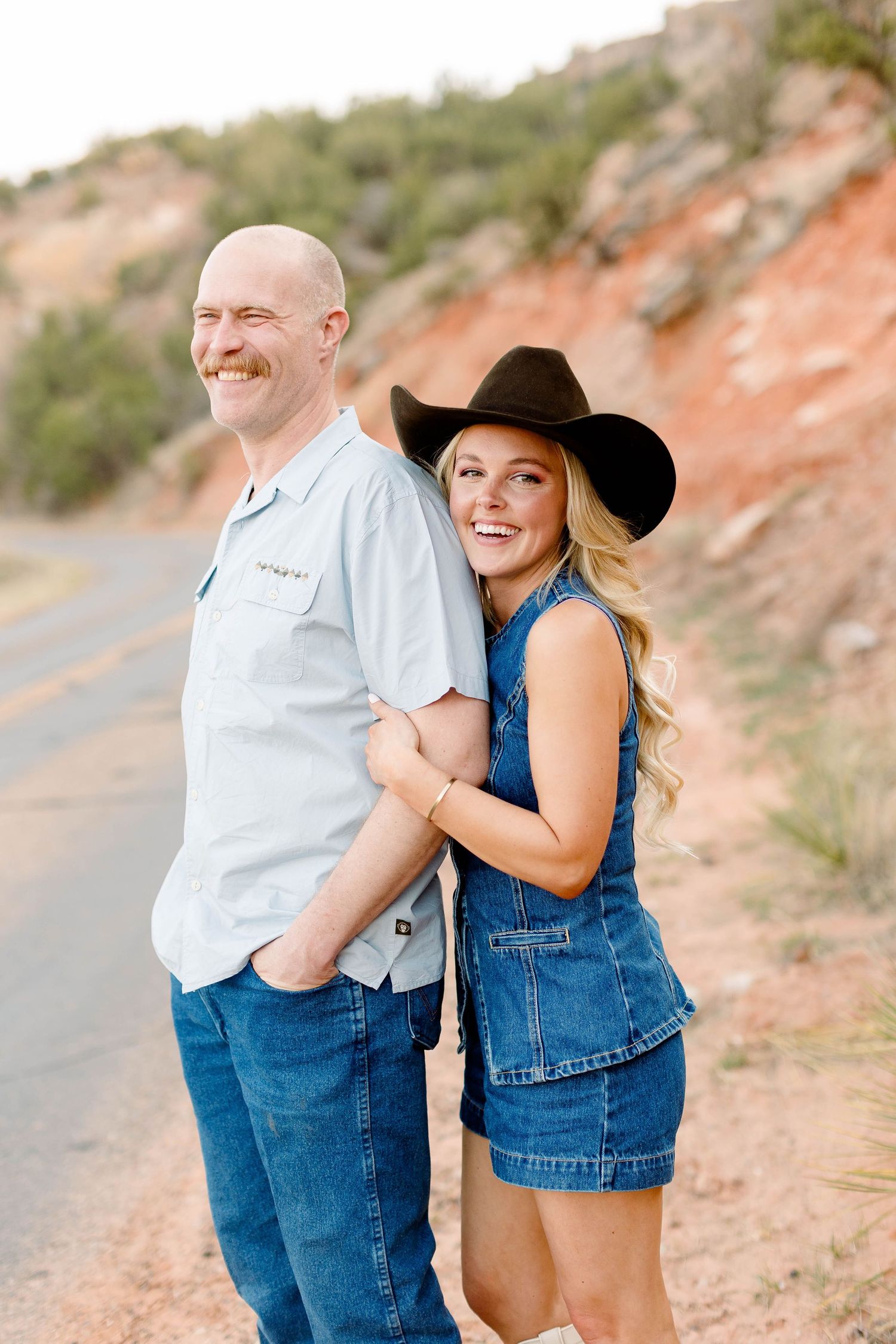 Candid moments of couple in casual wear having fun against desert landscape.