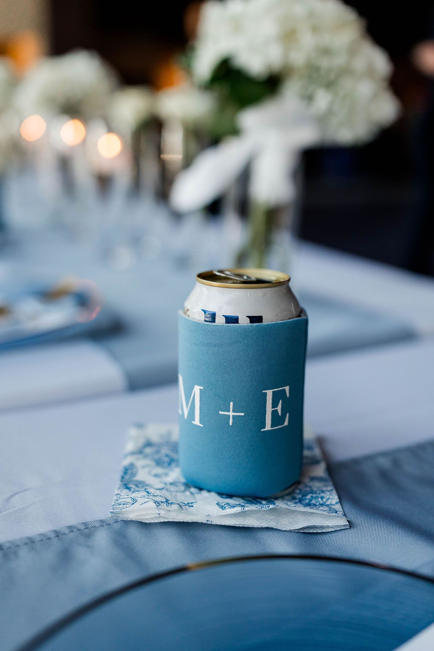 Light blue wedding favor boxes with monogram initials displayed on a white tablecloth.