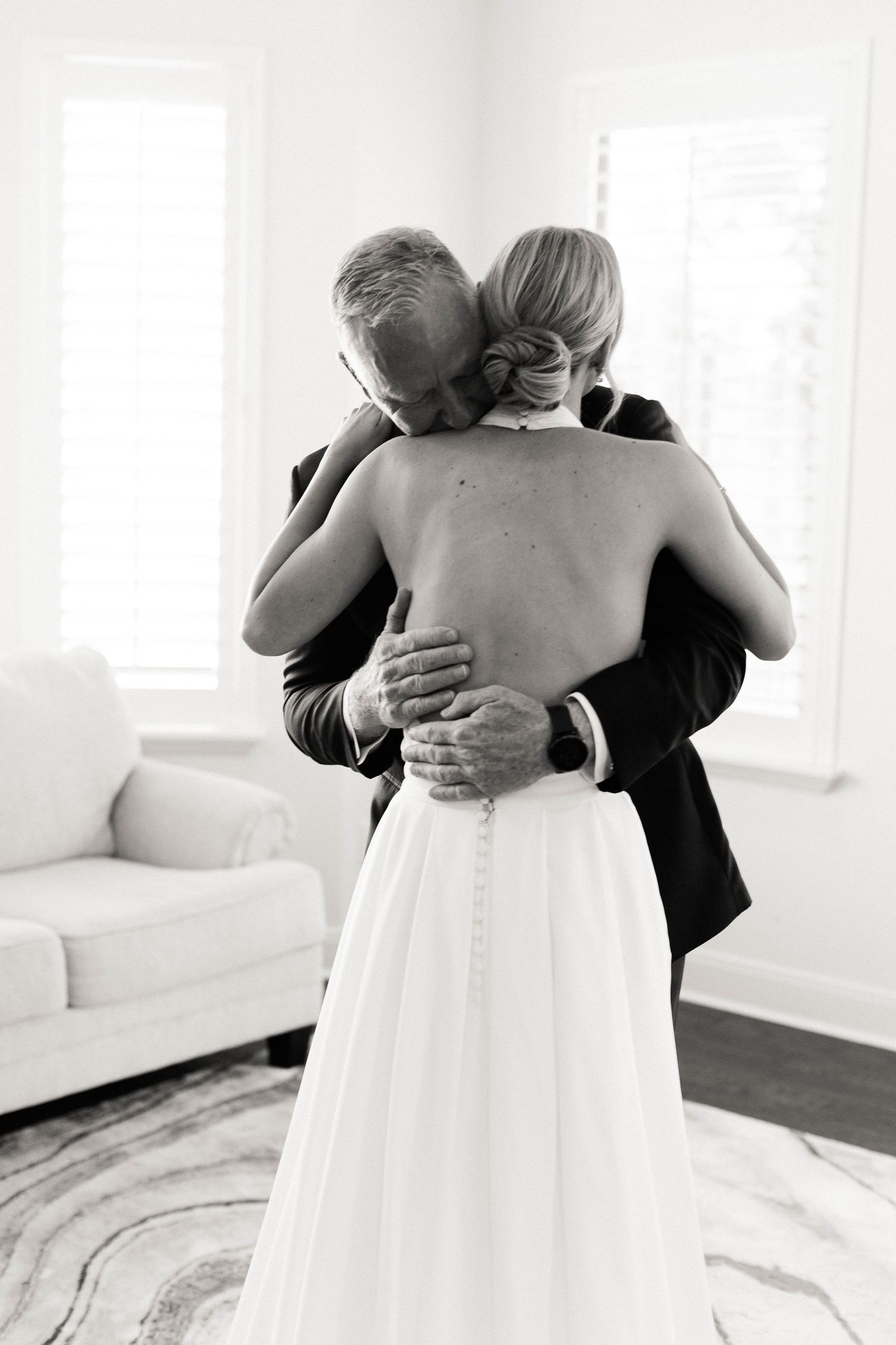 Black and white photo capturing an emotional embrace between two people in formal attire.