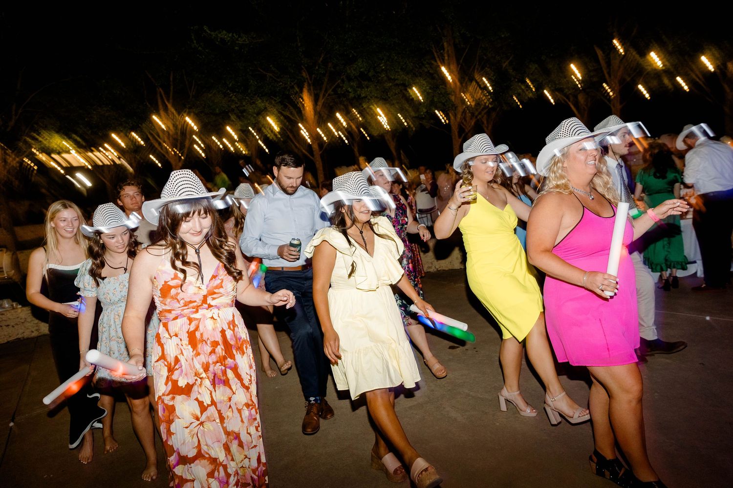 Wedding guests dancing and celebrating at an outdoor evening reception.