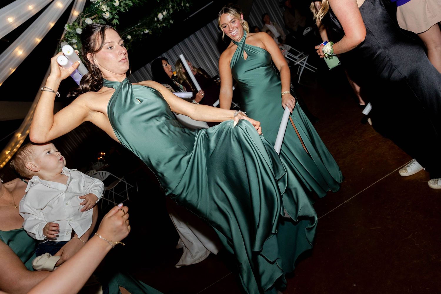 Wedding reception guests dance energetically on dark dance floor with dramatic lighting.