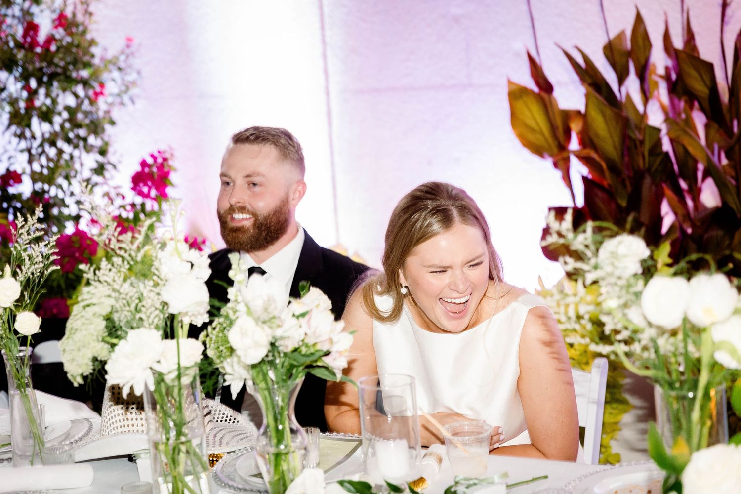 Colorful floral arrangements with pink and white flowers decorate wedding reception tables.