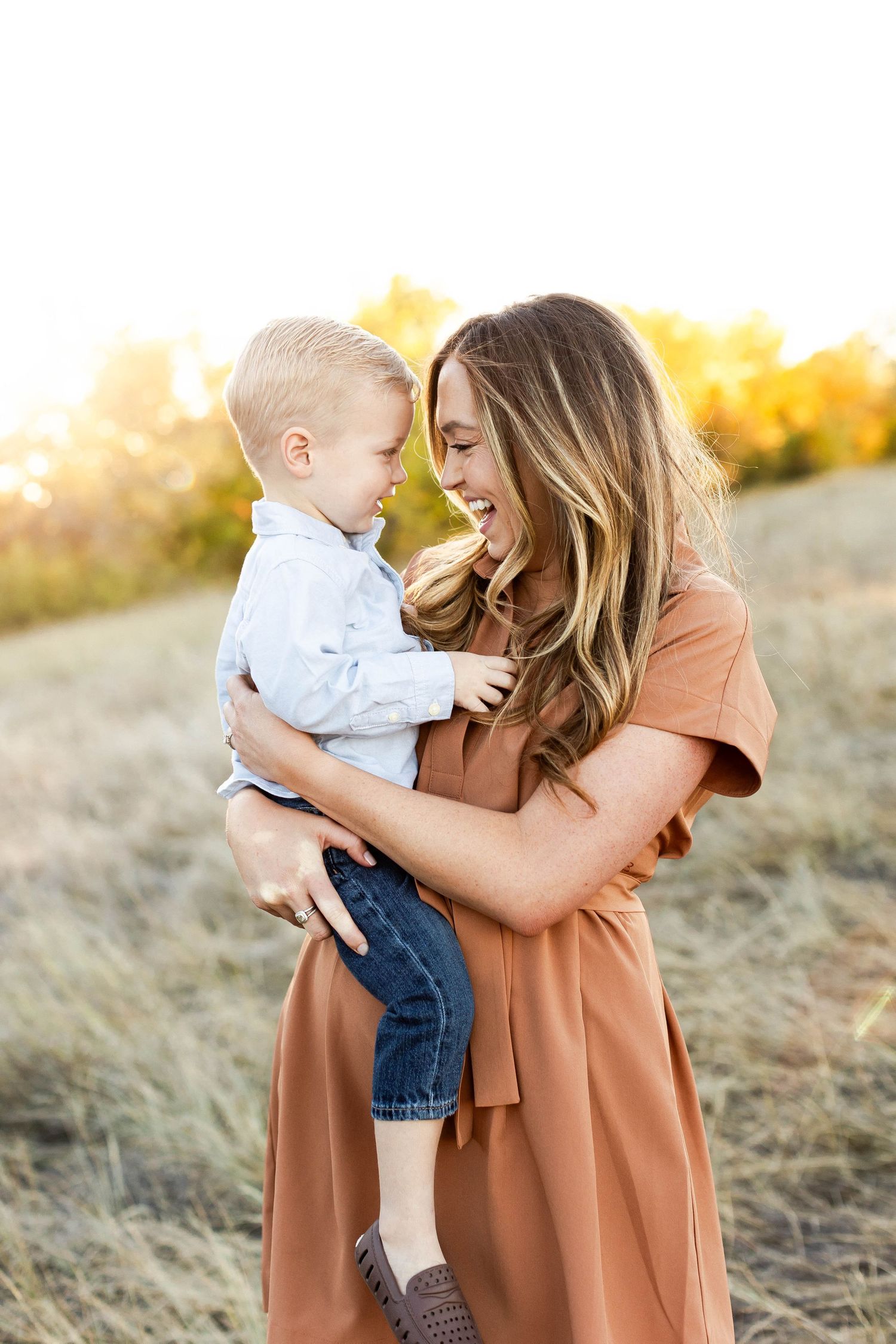 Parent and child share tender moment in sunlit field.