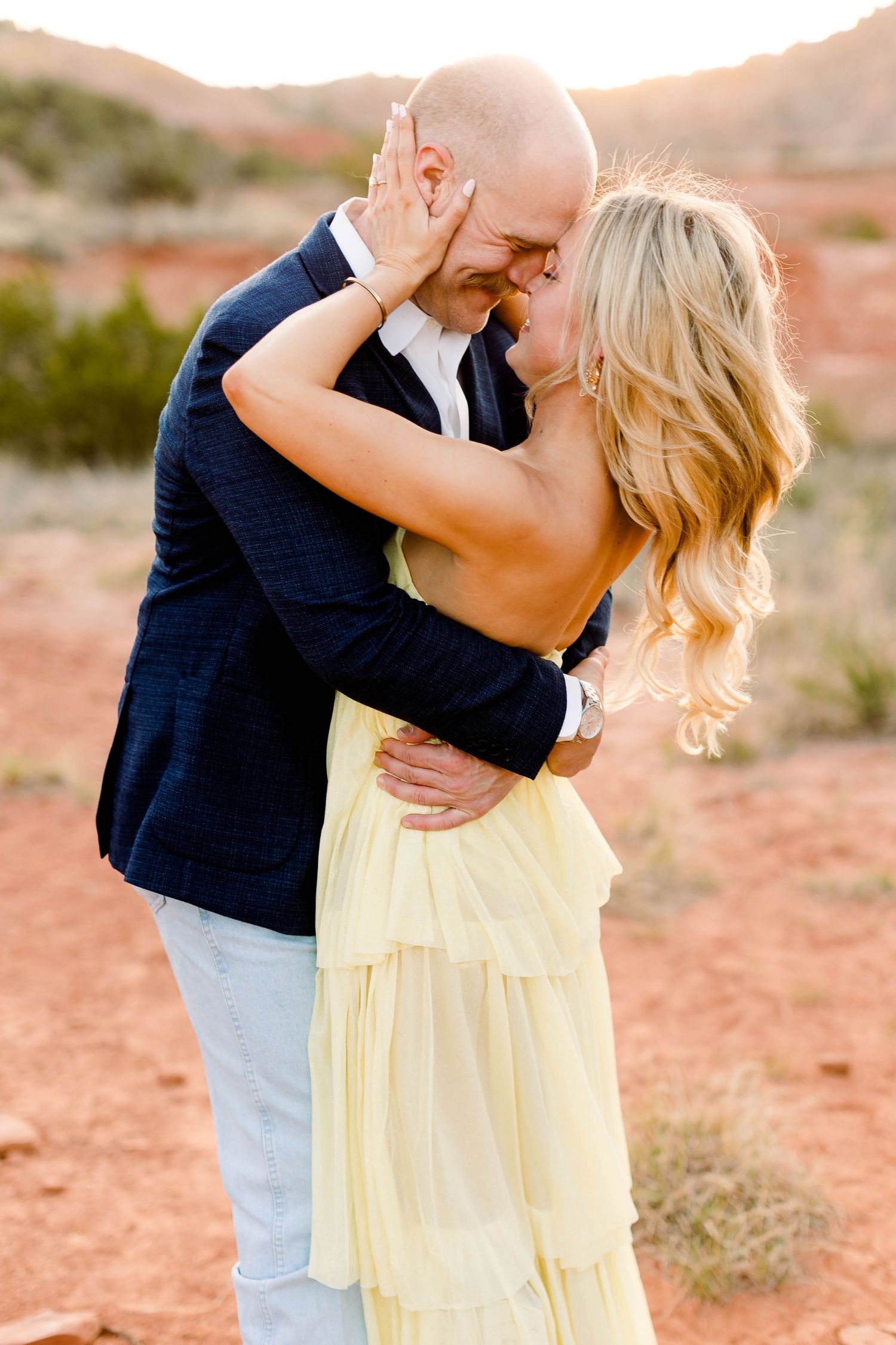 Affectionate couple shares romantic moments during desert sunset photography session.