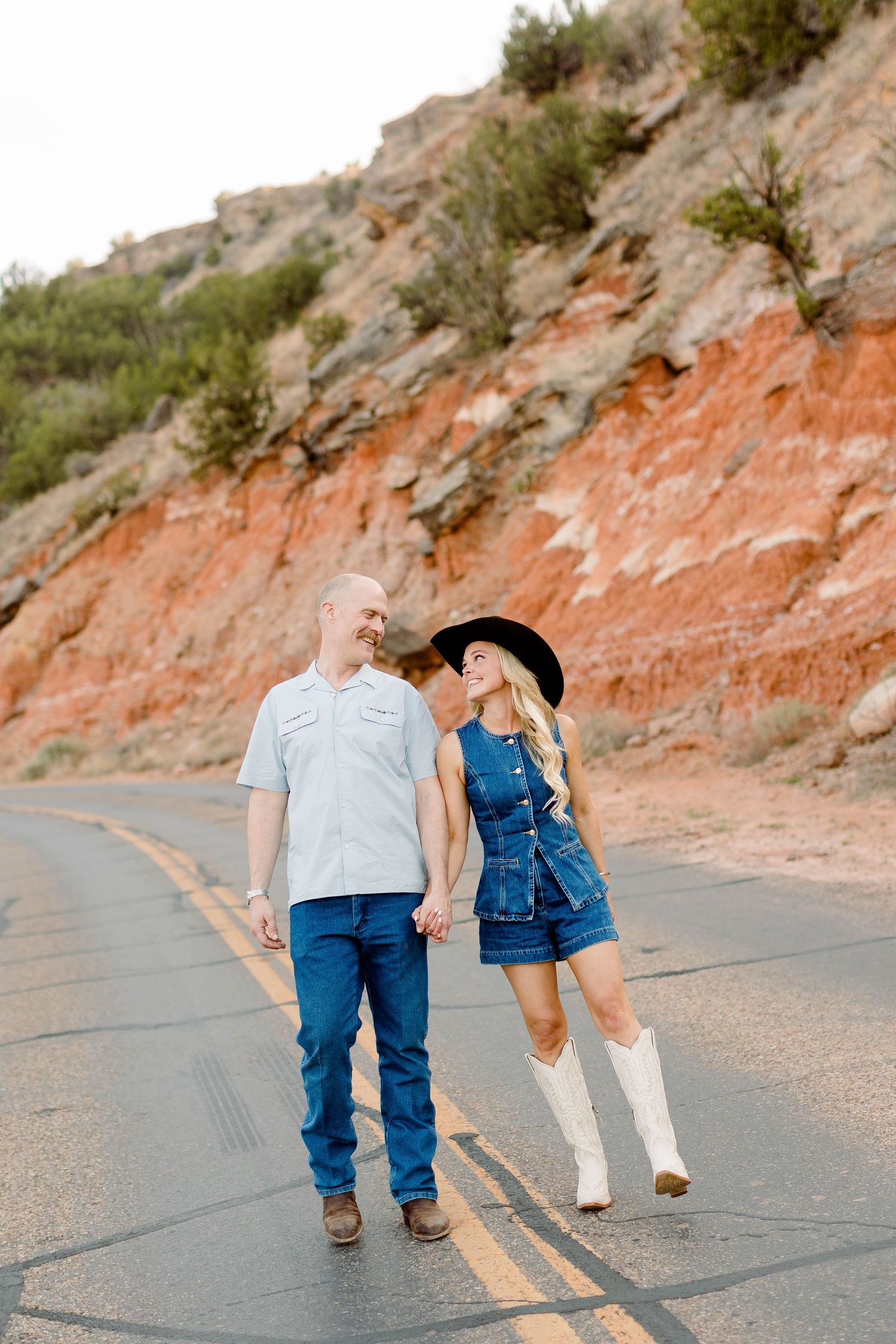 Couple walking away hand in hand on desert road during sunset photography session.