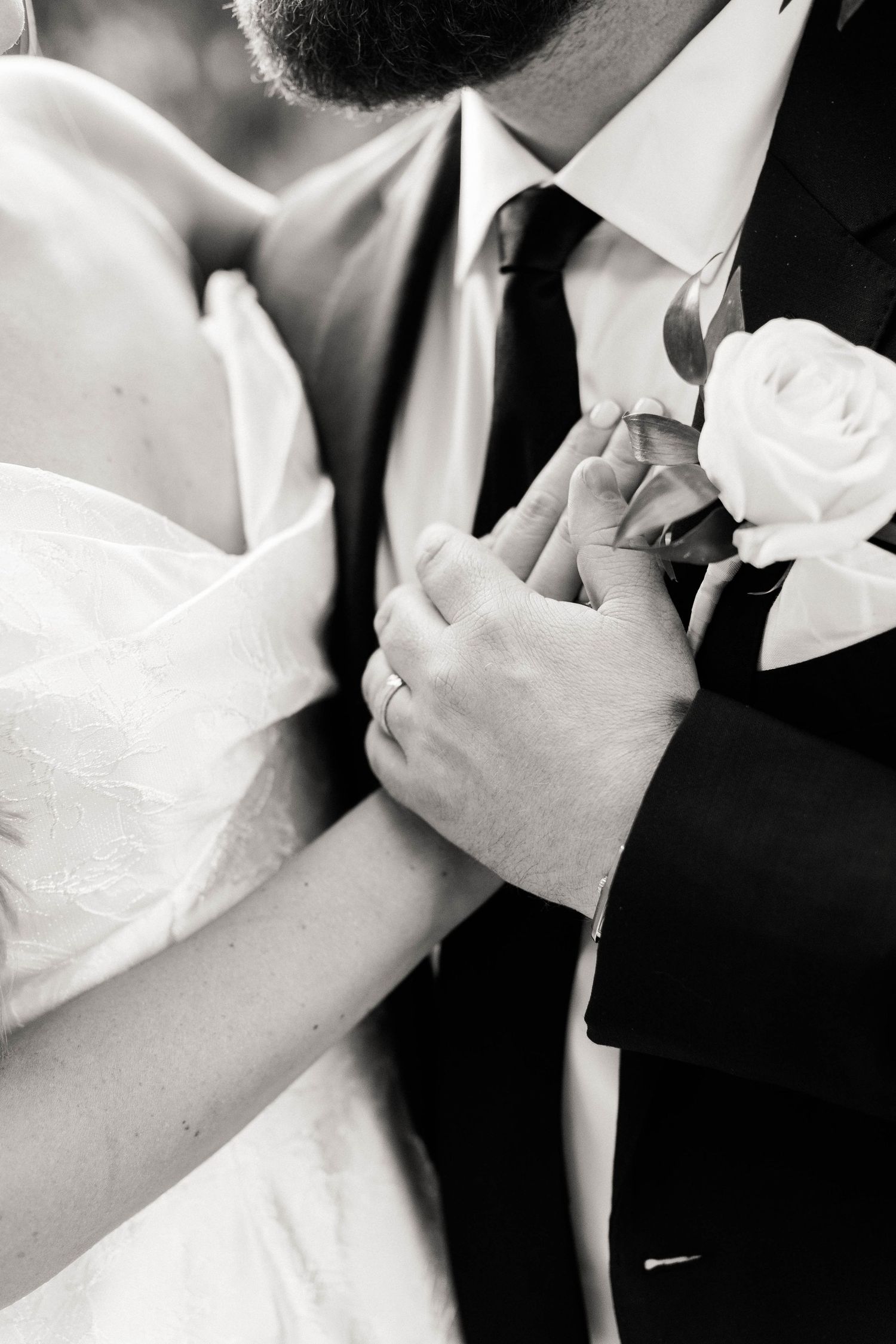 Black and white close-up photos of a groom adjusting his tie and bowtie during wedding preparations.